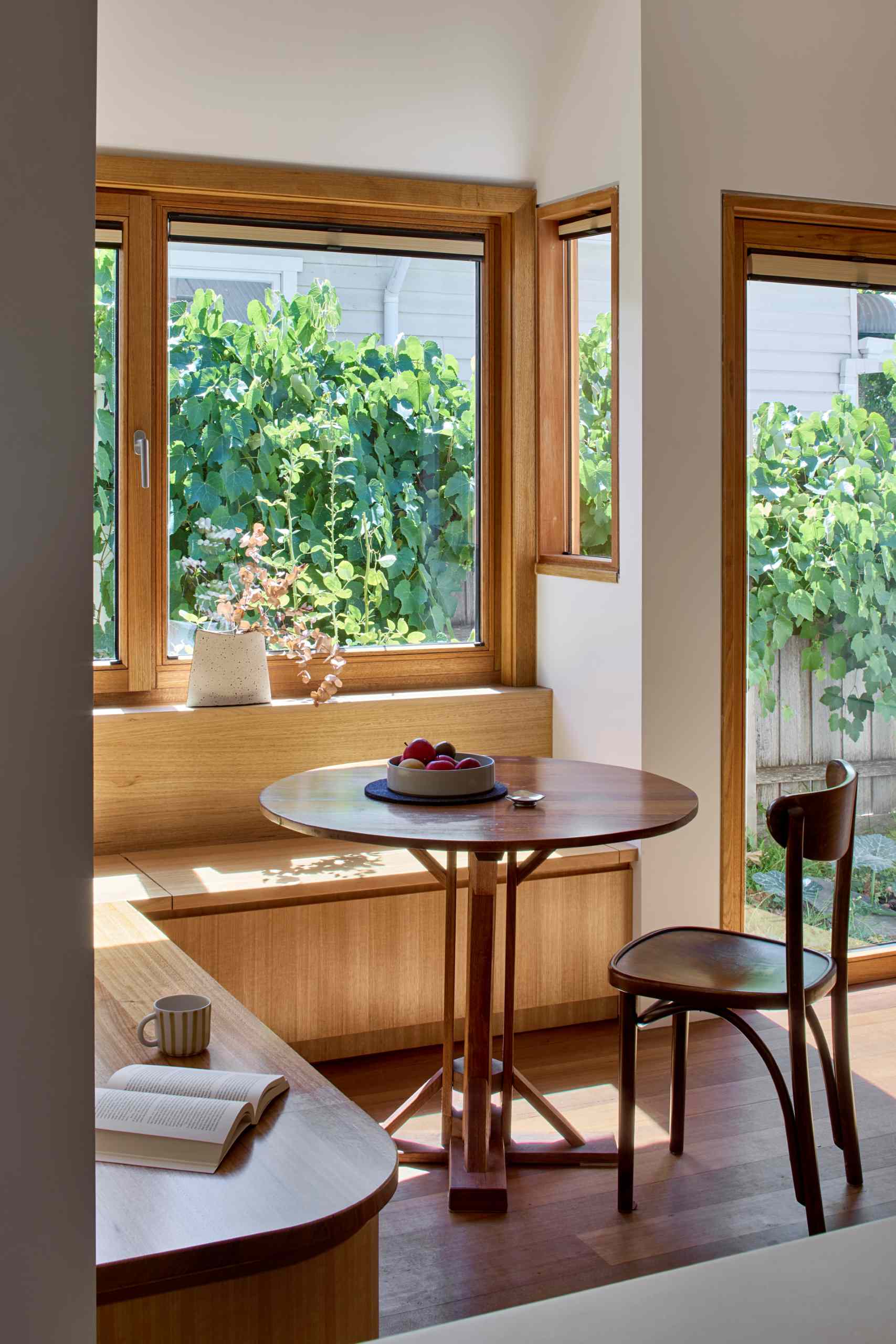A built-in breakfast nook with wood seating and views of the garden.