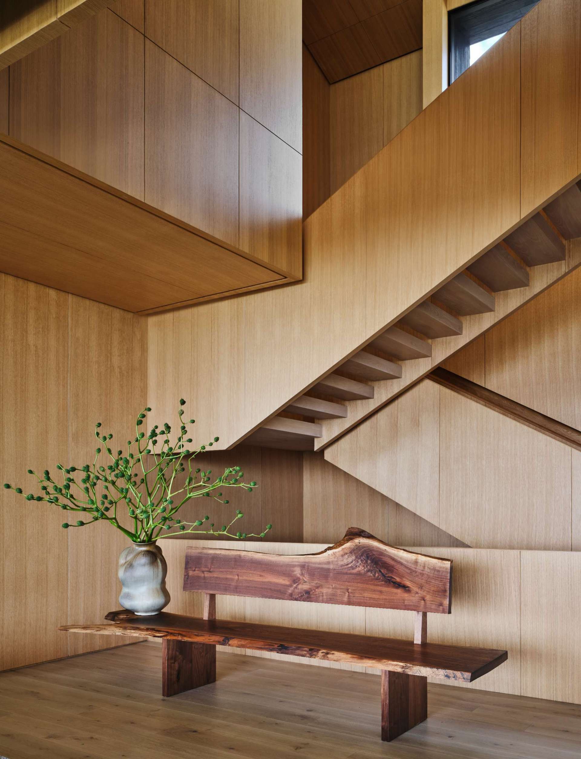 Wood stairs lead from the front door down to the social areas of the home.