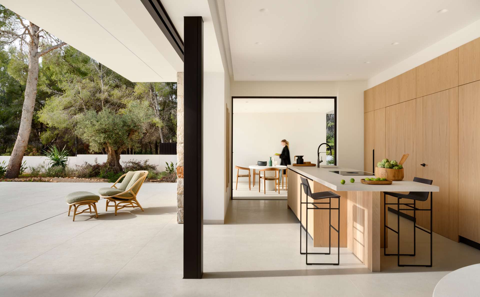 This light-filled kitchen embraces simplicity with flat-front oak cabinetry and a sleek stone topped island. Floor-to-ceiling doors blur the line between indoors and out, creating an airy transition to the natural landscape beyond.