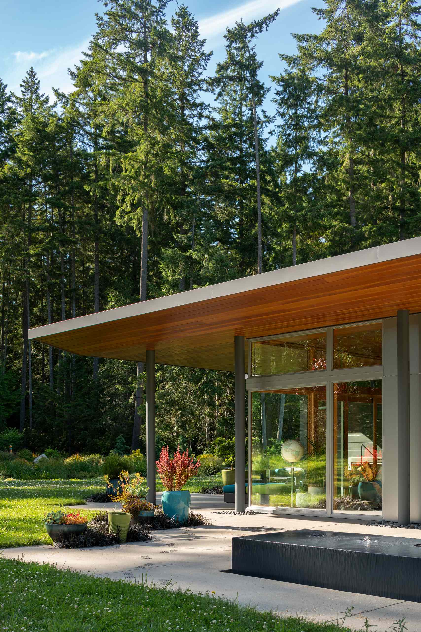 A modern home with a patio that's covered by the expansive roof.