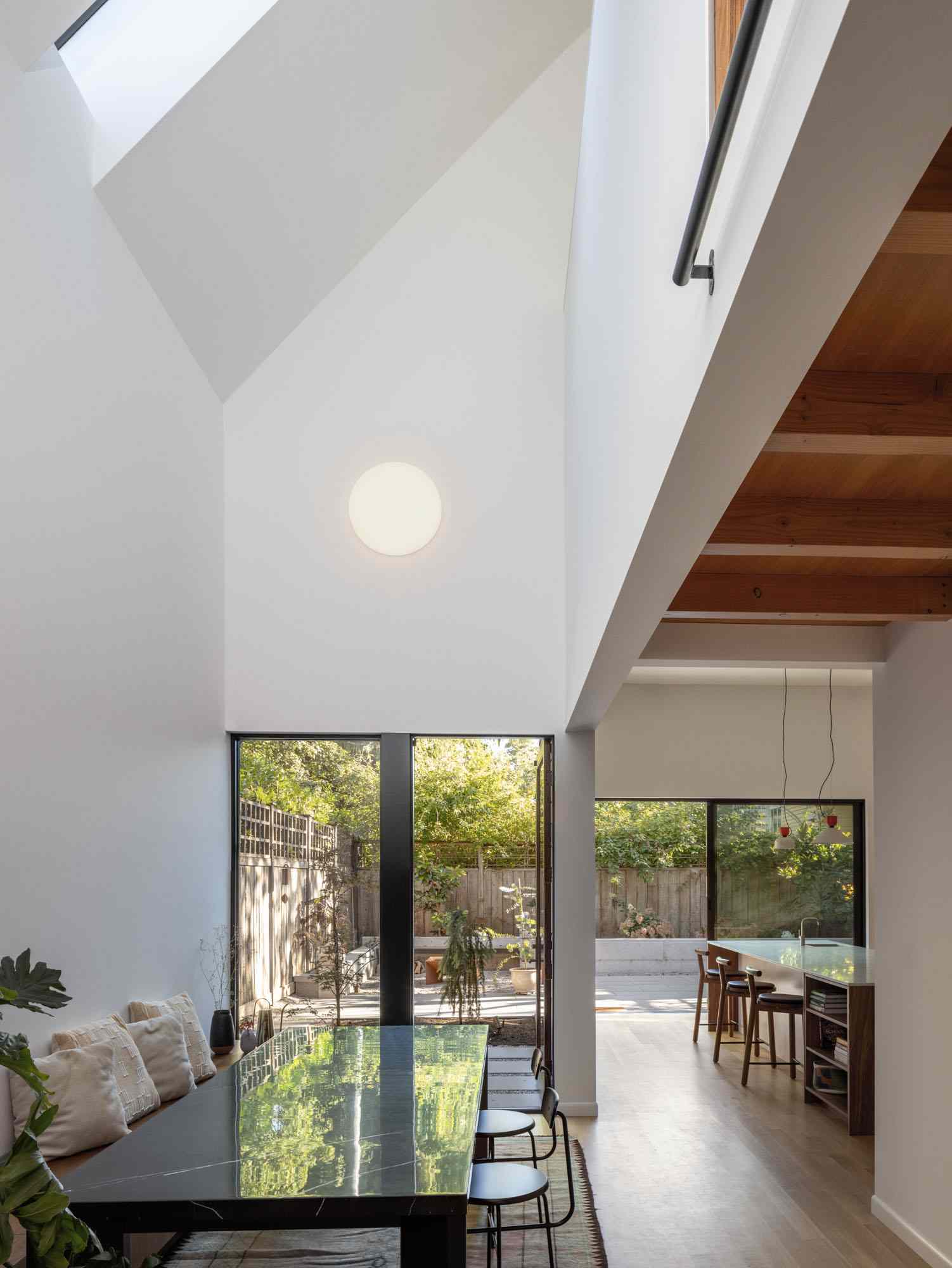 This dining area is centrally located and opens to a double-height space with eastern light and visual connection to the upper level.