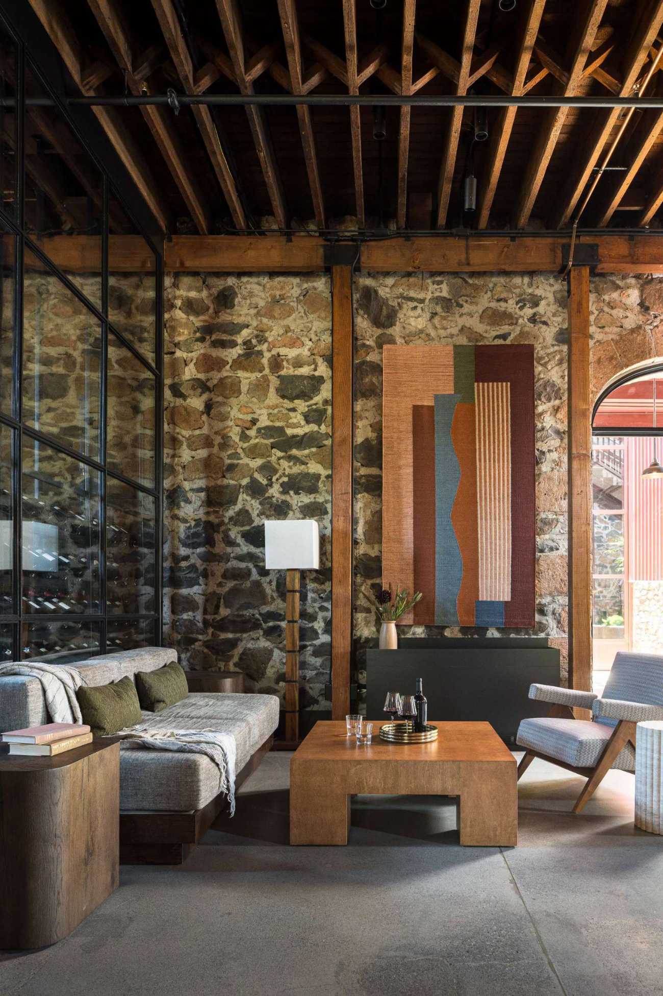 Subtle yet striking, the glass wine storage walls were seamlessly integrated into the architecture, serving as both a functional element and a visual anchor. Their vertical proportions draw the eye upward, emphasizing the building’s original height, while the dark framing adds a clean, modern contrast to the warm, timeworn materials throughout the space.