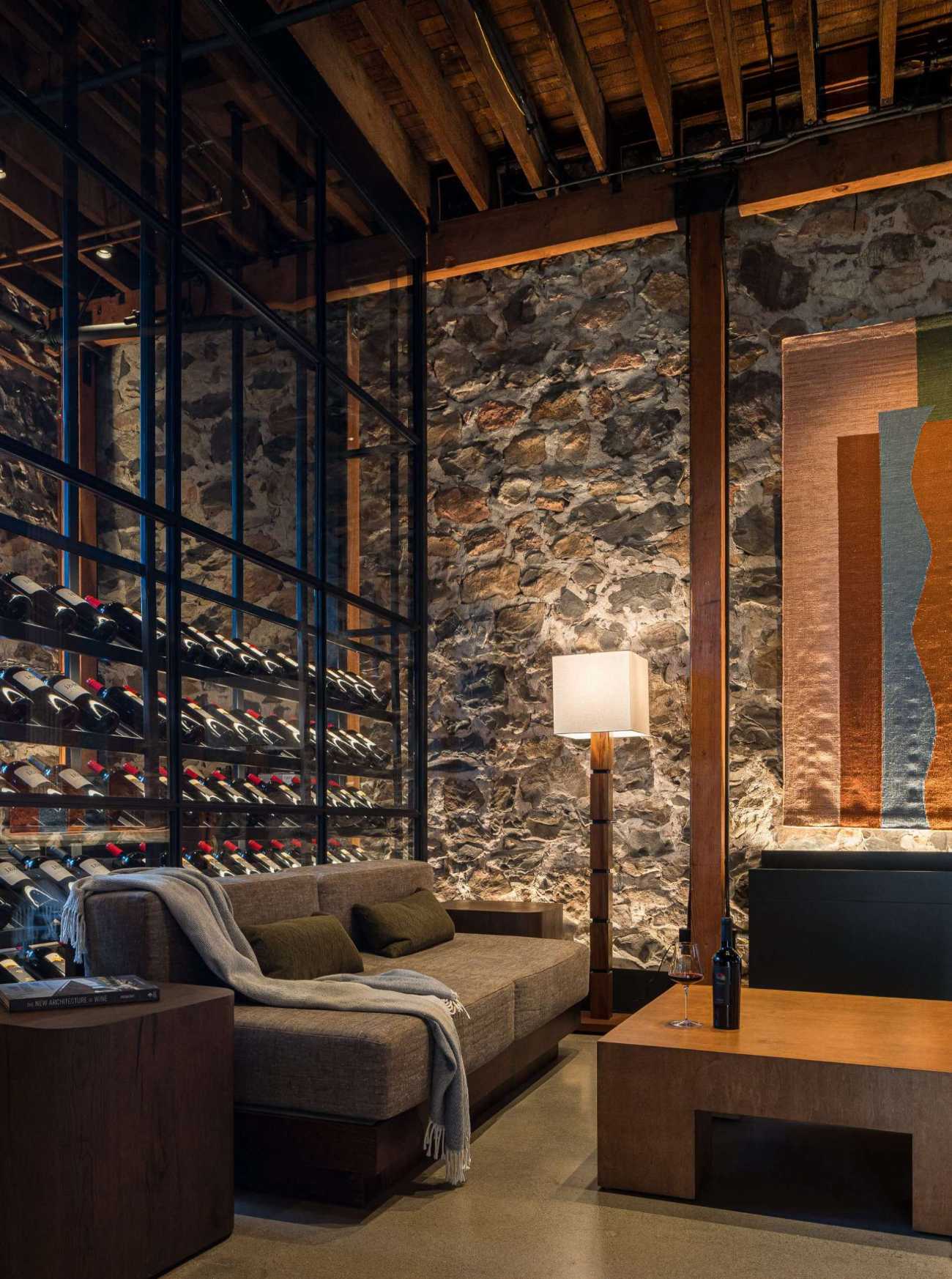 Subtle yet striking, the glass wine storage walls were seamlessly integrated into the architecture, serving as both a functional element and a visual anchor. Their vertical proportions draw the eye upward, emphasizing the building’s original height, while the dark framing adds a clean, modern contrast to the warm, timeworn materials throughout the space.