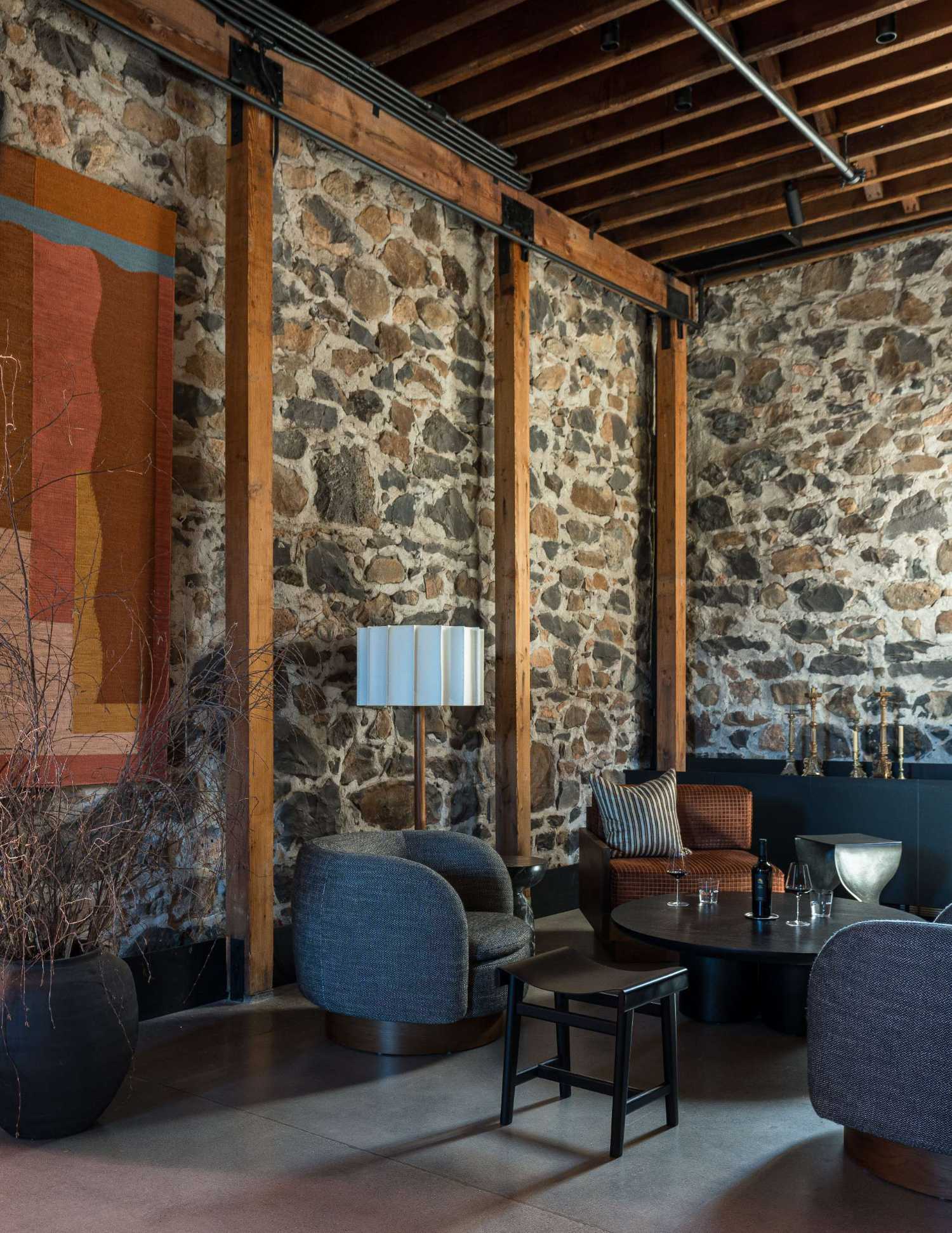 Jeanneret-inspired lounge chairs and tweed swivel chairs inject a sense of playful sophistication in this Napa Valley wine tasting room, while custom tapestries by London-based artist Sussy Cazalet add vibrant color and artisanal richness.