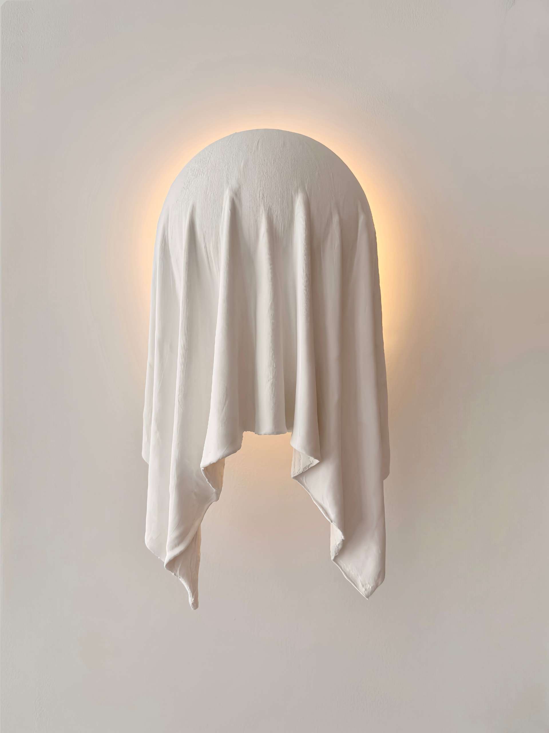 The Requiem Wall Light, handcrafted in plaster using a unique sculpting technique, captures the fluidity of draped fabric in a striking wall-mounted form.