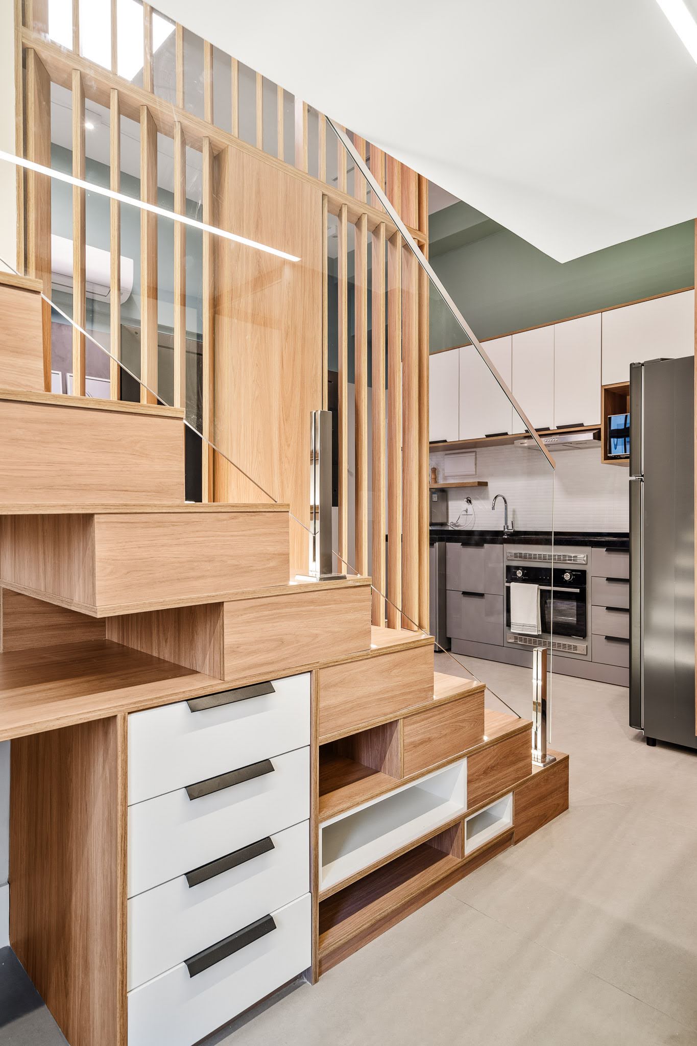 This home office is cleverly integrated beneath the staircase, making full use of an often-overlooked space, with the desk and storage areas fitting seamlessly into the custom carpentry and serves as a functional workspace without interrupting the apartment’s flow.