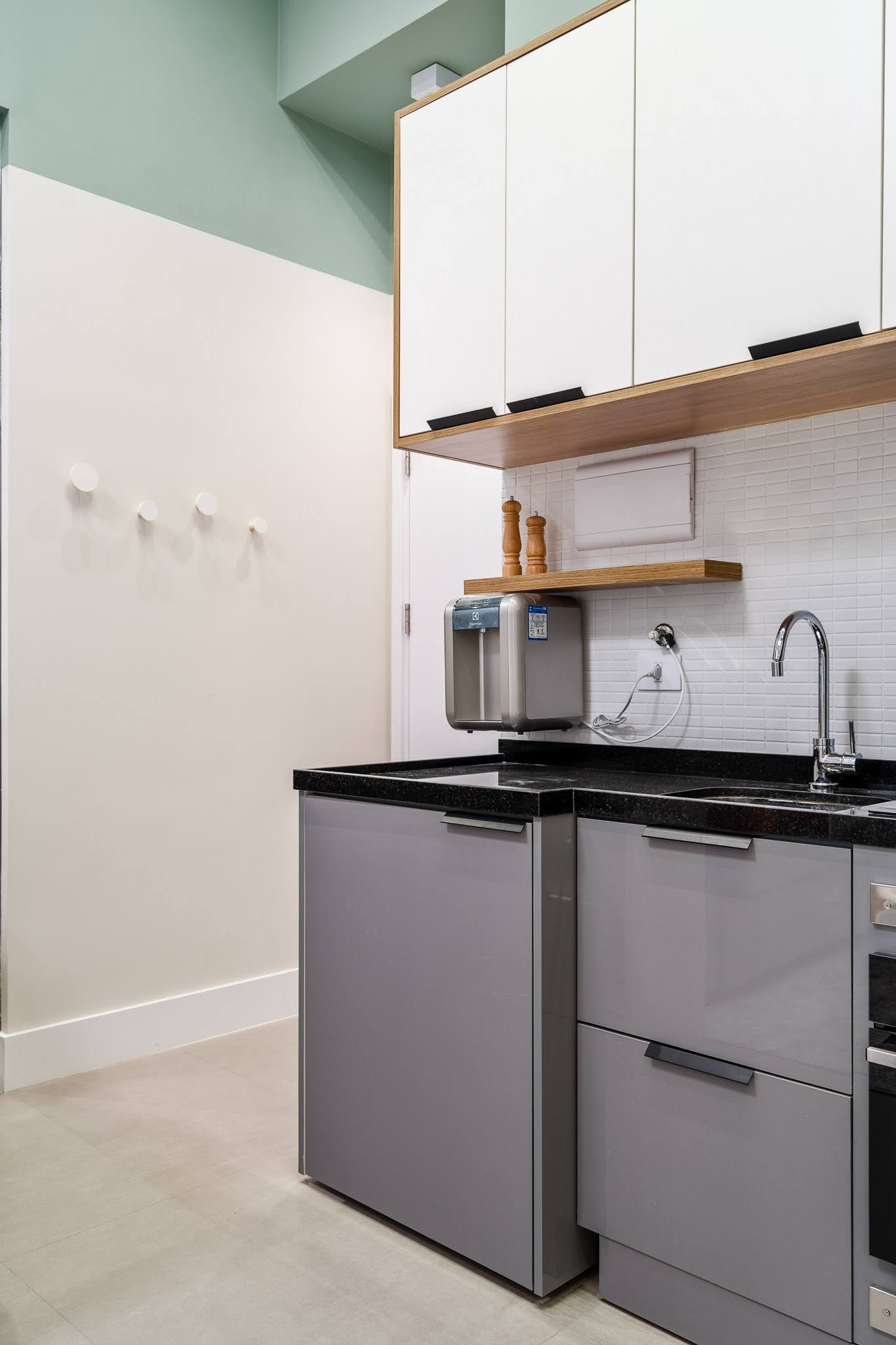 In the kitchen of this small apartment, cabinetry in Sacred Gray and white MDF provides ample storage while maintaining a clean, uniform look that blends seamlessly with the surrounding design elements.