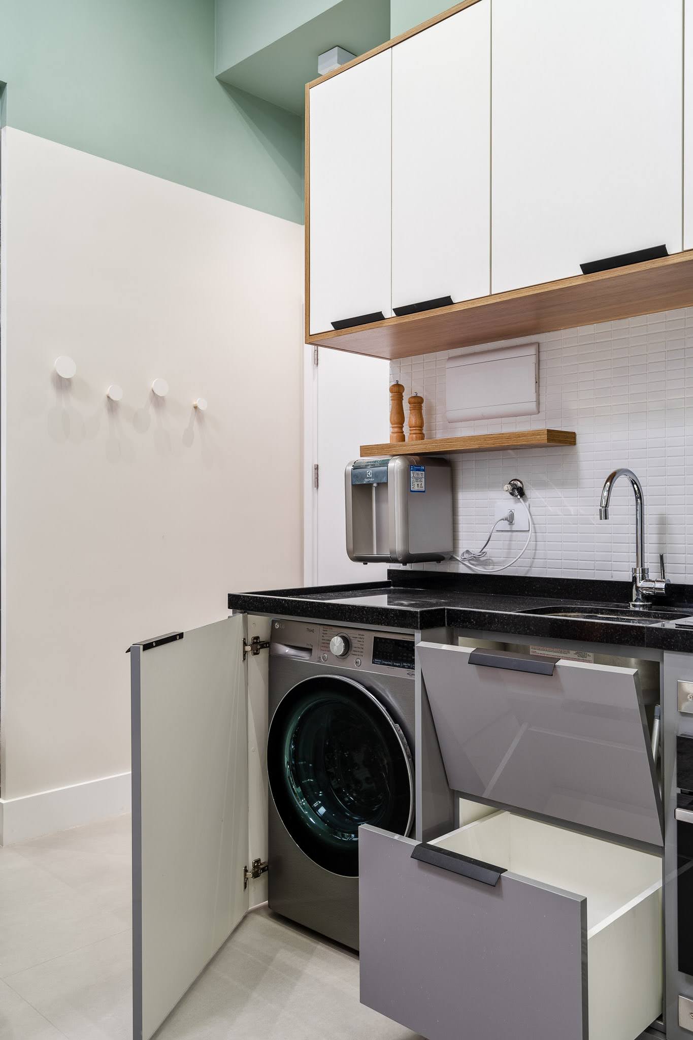 In the kitchen of this small apartment, cabinetry in Sacred Gray and white MDF provides ample storage while maintaining a clean, uniform look that blends seamlessly with the surrounding design elements.