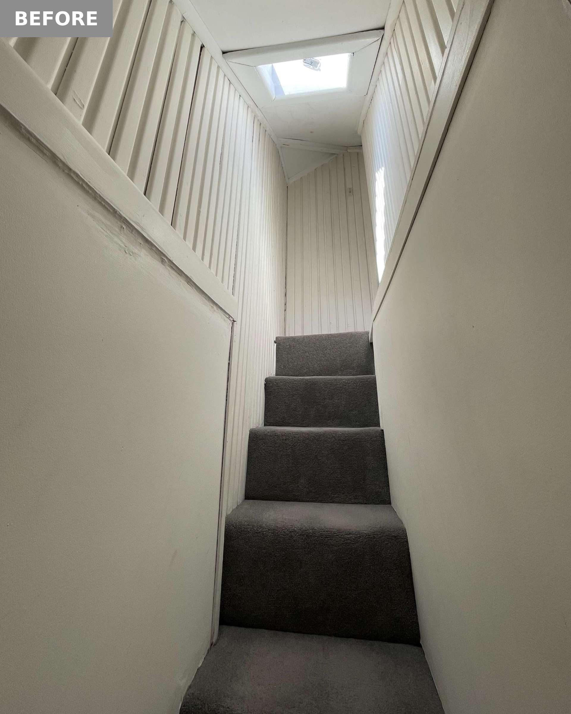 The original staircase was narrow with steep steps, dark grey carpet, and white timber paneling. A small skylight provided limited light, highlighting the cramped layout.