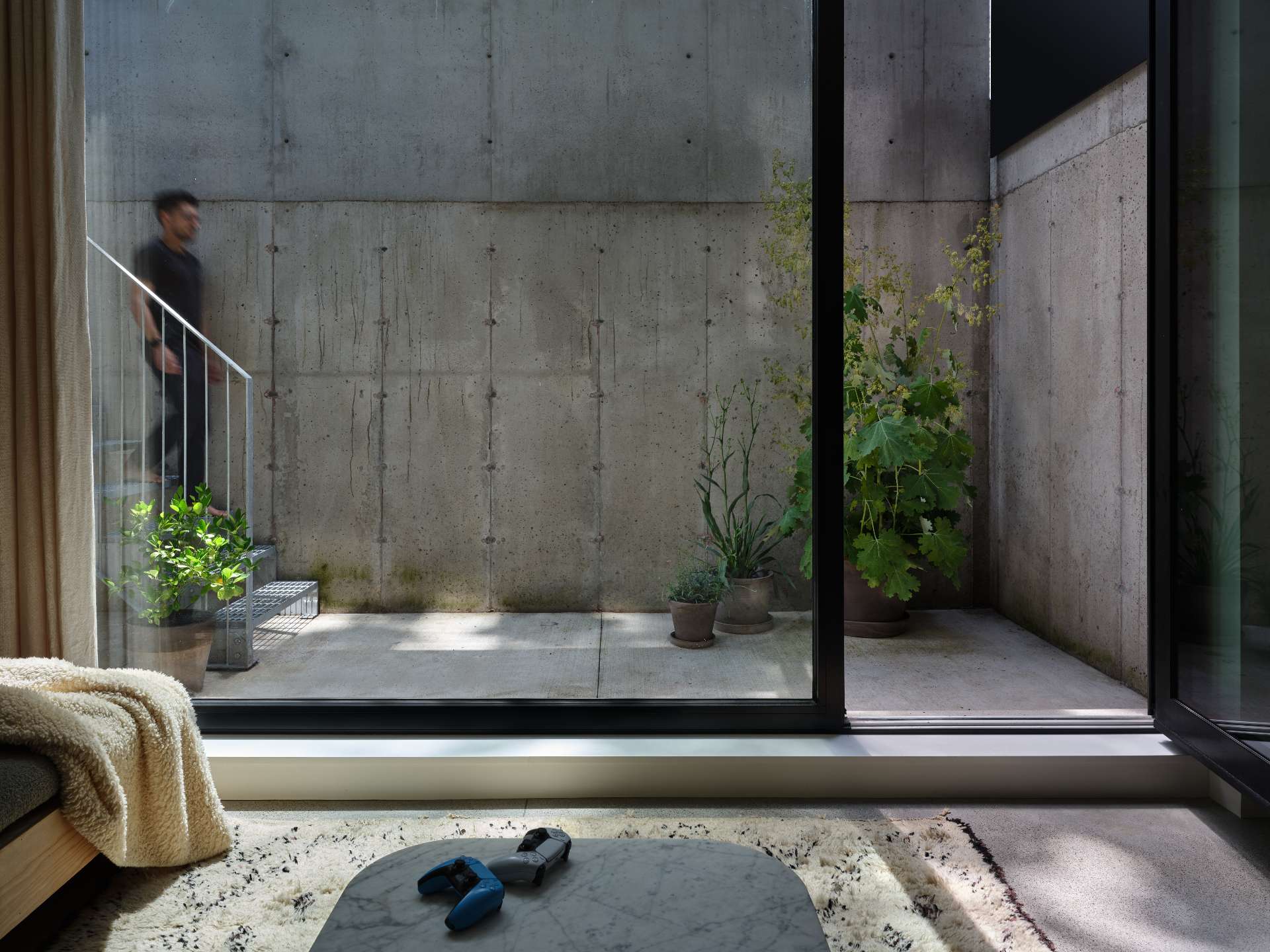 A standout feature of this modern home is the sunken basement courtyard, accessed via concrete steps and framed by cast-in-place retaining walls. This private outdoor retreat opens off the recreation room and receives warm southern light.