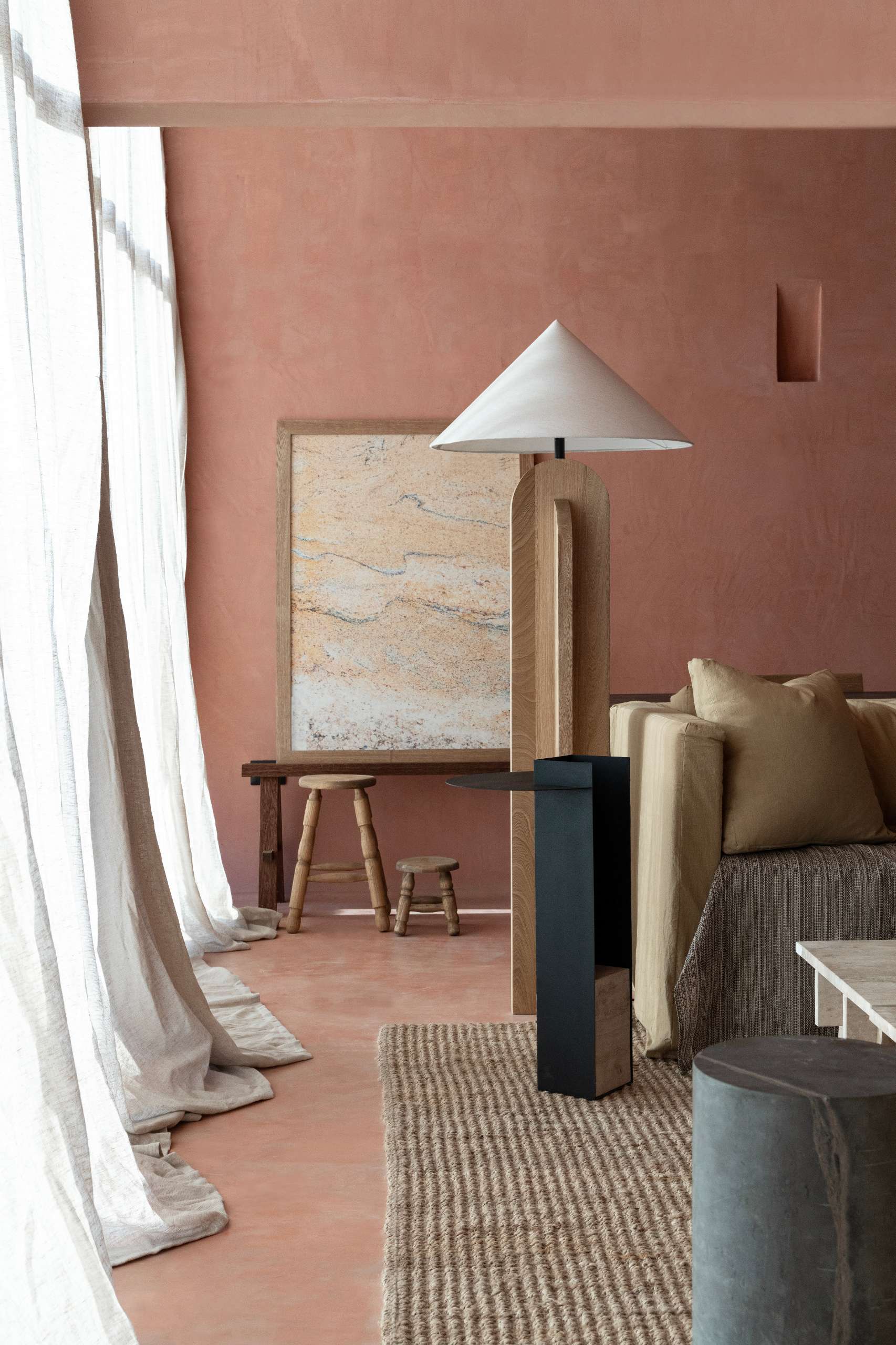 A serene, terracotta-toned living space showcases earthy textures, warm natural light, and a refined material palette. Walls in sunbaked hues form a calming backdrop for relaxed sofas, woven rugs, and solid wood furniture with primitive silhouettes.
