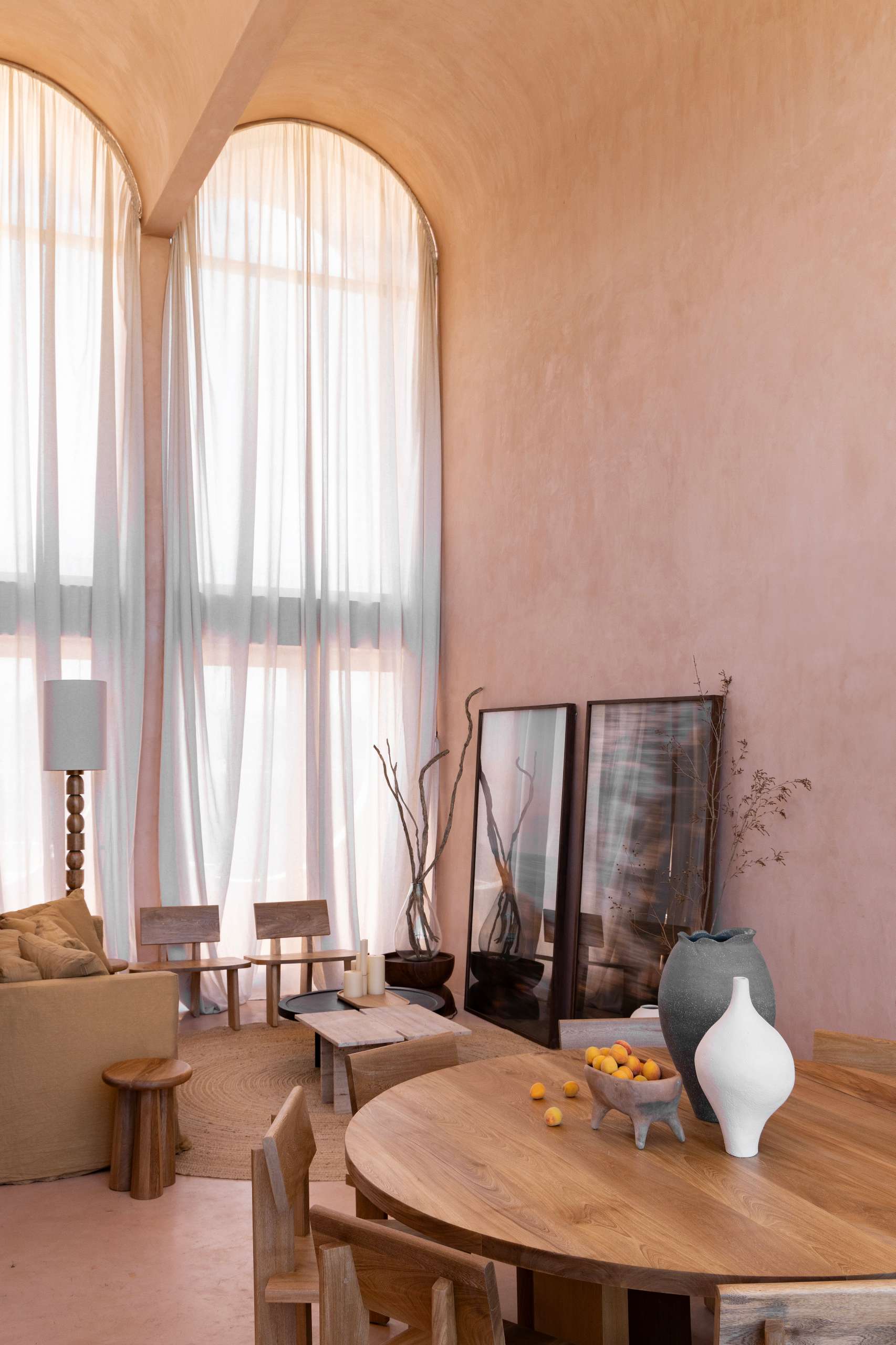 A serene, terracotta-toned living space showcases earthy textures, warm natural light, and a refined material palette. Walls in sunbaked hues form a calming backdrop for relaxed sofas, woven rugs, and solid wood furniture with primitive silhouettes.