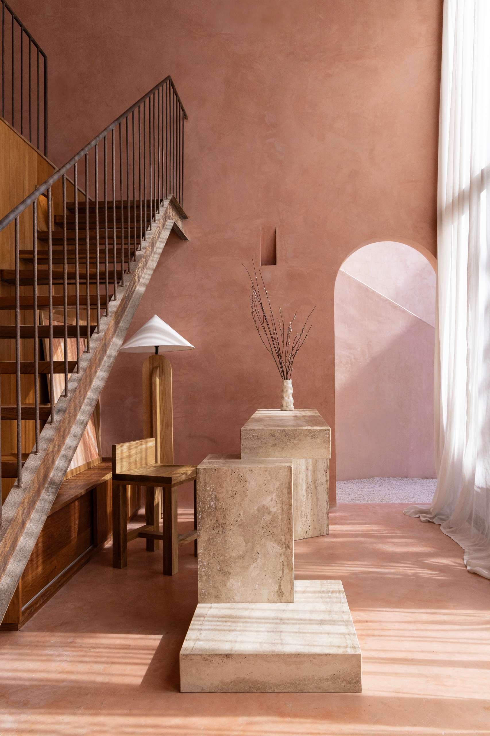 A serene, terracotta-toned living space showcases earthy textures, warm natural light, and a refined material palette. Walls in sunbaked hues form a calming backdrop for relaxed sofas, woven rugs, and solid wood furniture with primitive silhouettes.