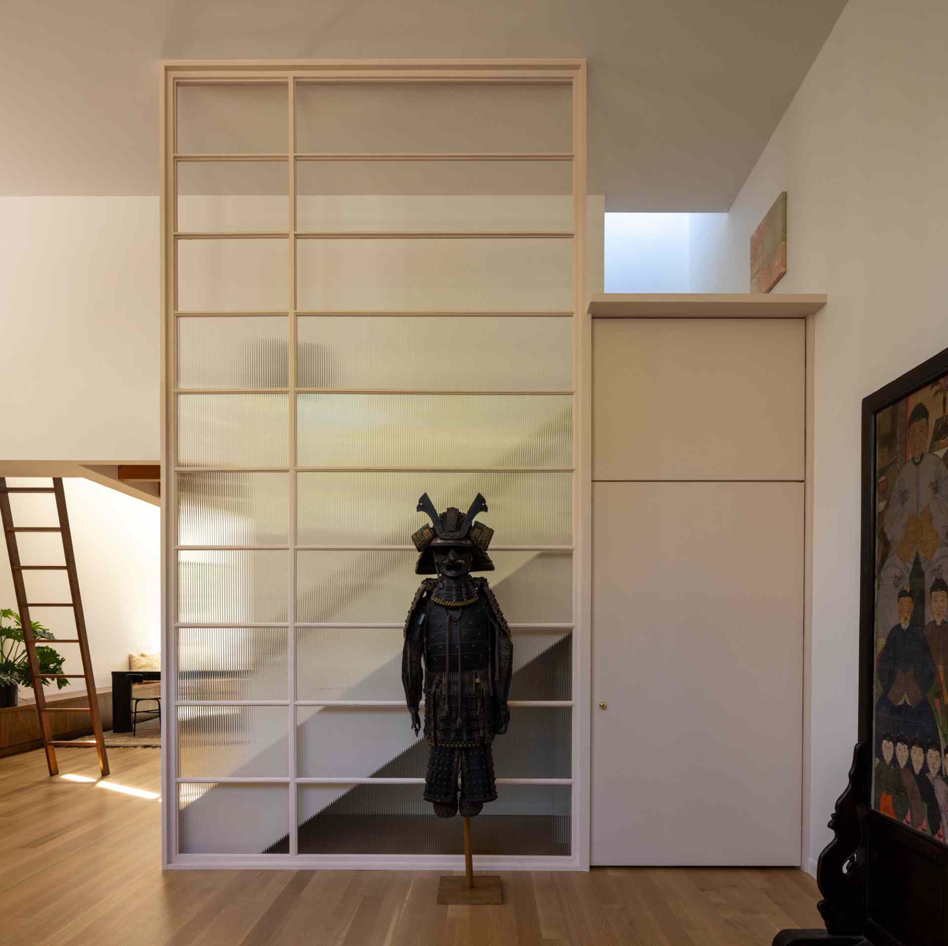 The frame of a replaced window was repurposed as an interior screen and stair guardrail, while small doors hide storage underneath the stairs.