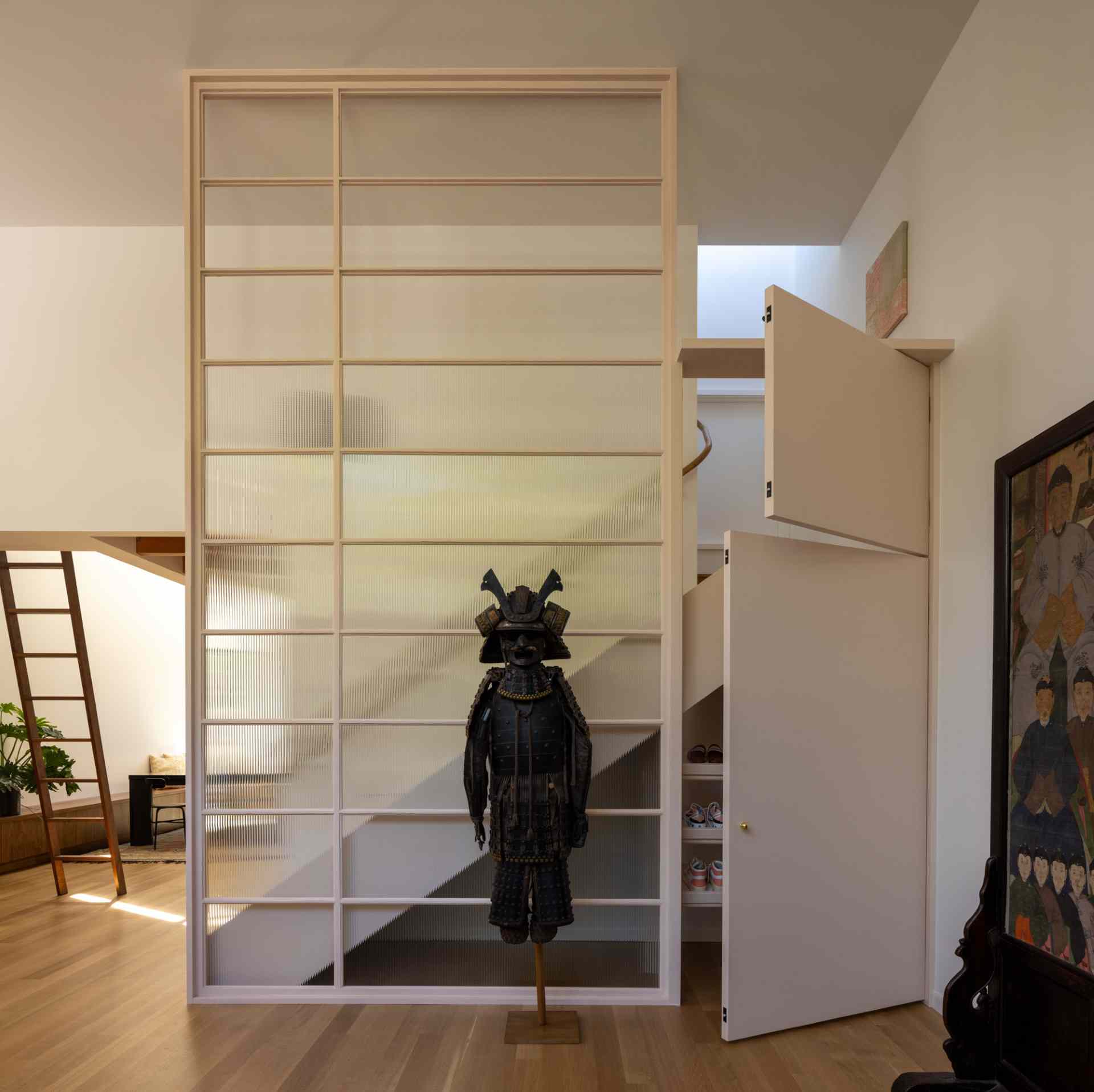 The frame of a replaced window was repurposed as an interior screen and stair guardrail, while small doors hide storage underneath the stairs.