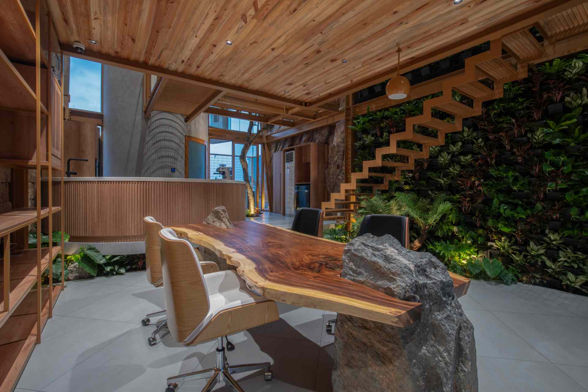 A structured meeting area combines sleek shelving with raw materials like stone and timber. Soft daylight and a green wall create a calm, inviting space that feels more like a retreat than a typical office.