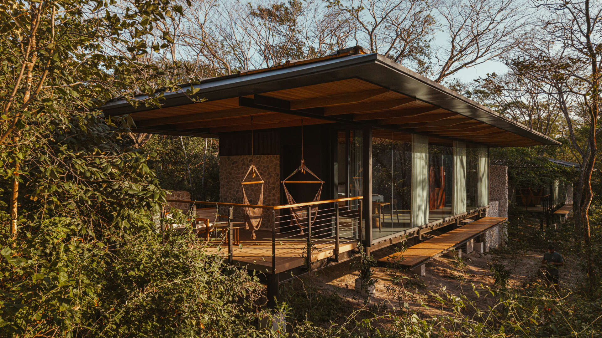 A stone, wood, and glass clad jungle bungalow in Costa Rica blends effortlessly into its forest surroundings.