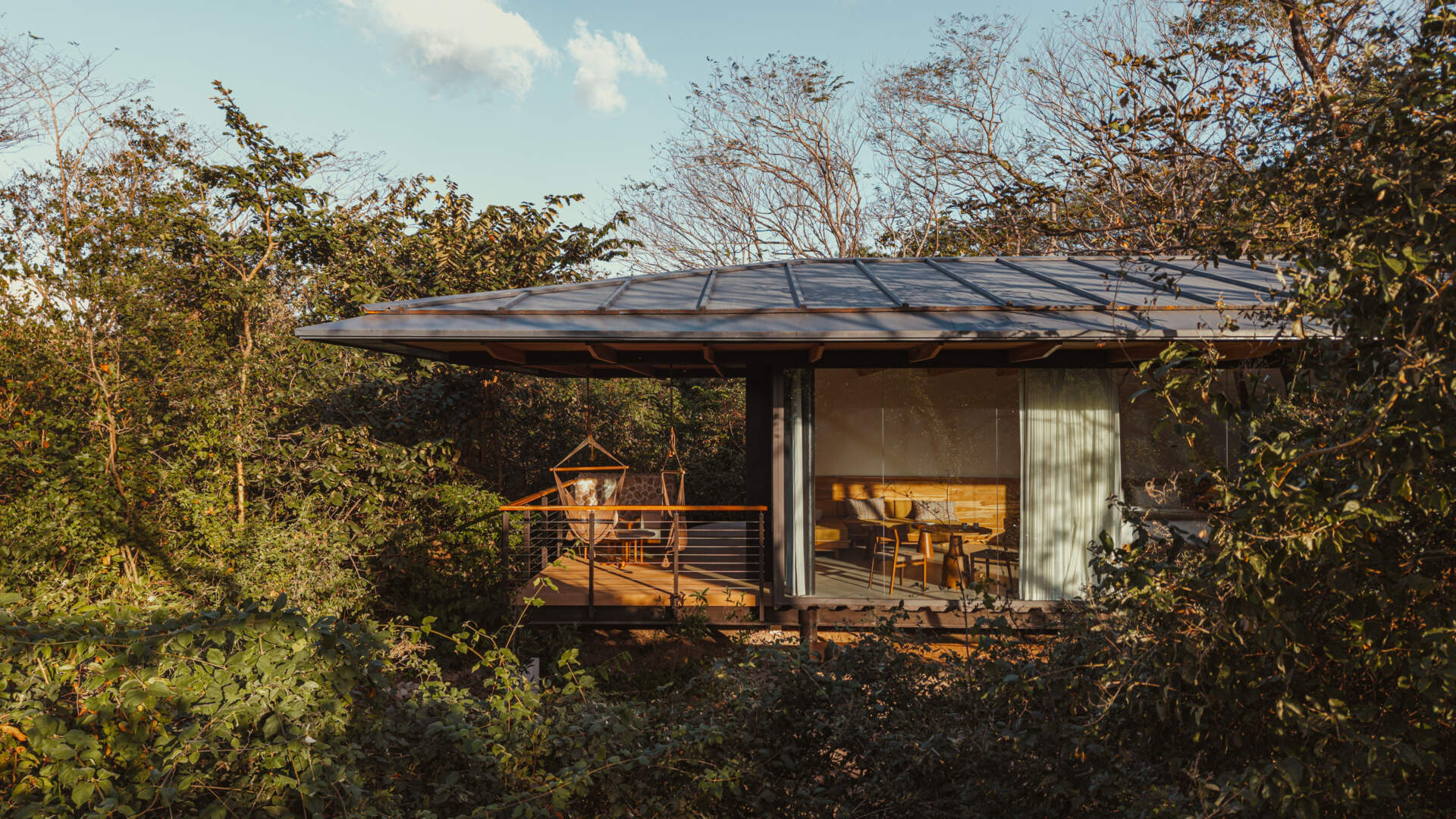 A stone, wood, and glass clad jungle bungalow in Costa Rica blends effortlessly into its forest surroundings.