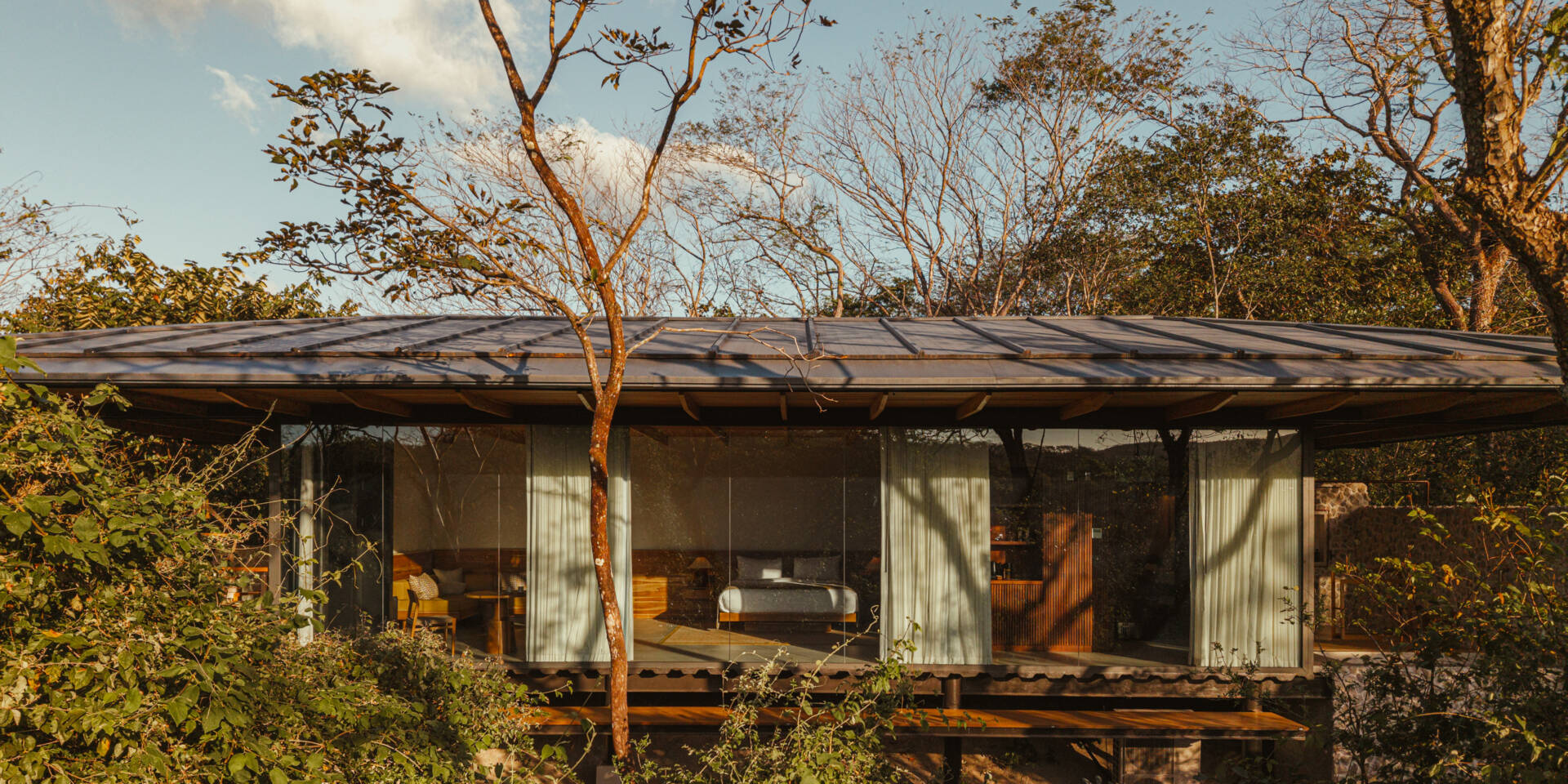 A stone, wood, and glass clad jungle bungalow in Costa Rica blends effortlessly into its forest surroundings.
