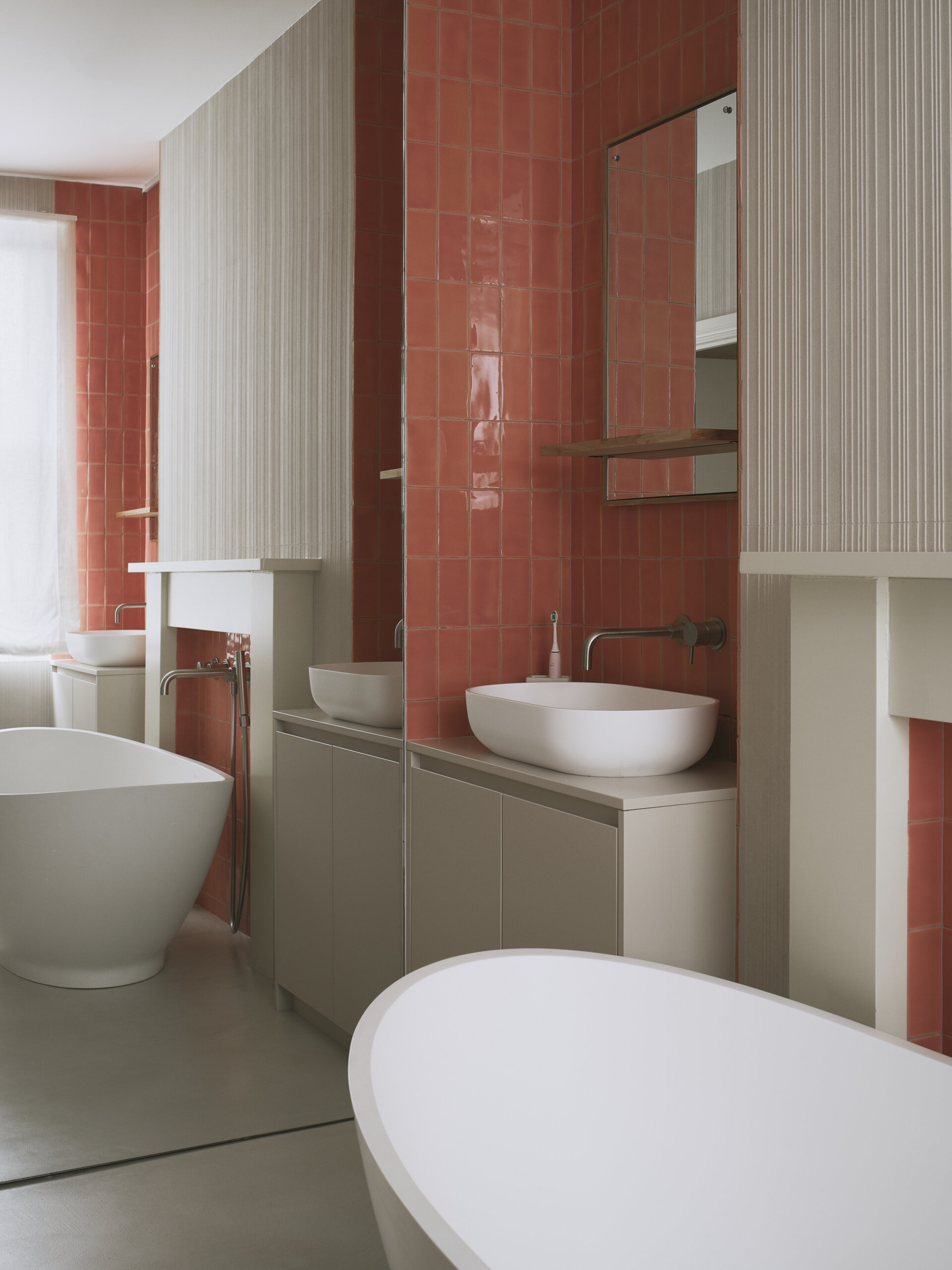 This bathroom blends old and new with glazed terracotta tiles, dual vanities, and a freestanding bathtub, all while keeping the space feeling calm and understated. Subtle textures and layered details add depth, and original features are reworked to quietly reflect the home’s Victorian roots.