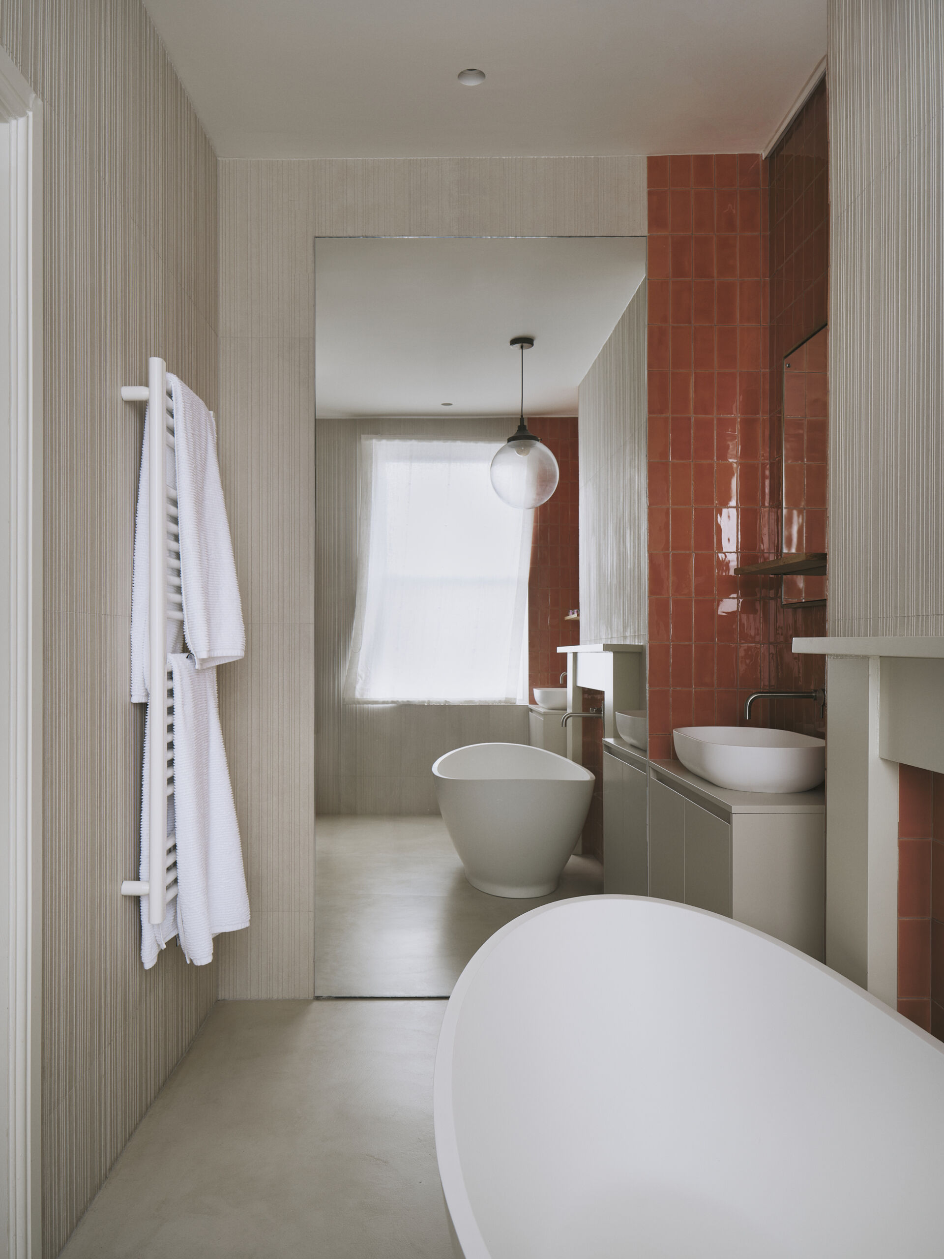 This bathroom blends old and new with glazed terracotta tiles, dual vanities, and a freestanding bathtub, all while keeping the space feeling calm and understated. Subtle textures and layered details add depth, and original features are reworked to quietly reflect the home’s Victorian roots.