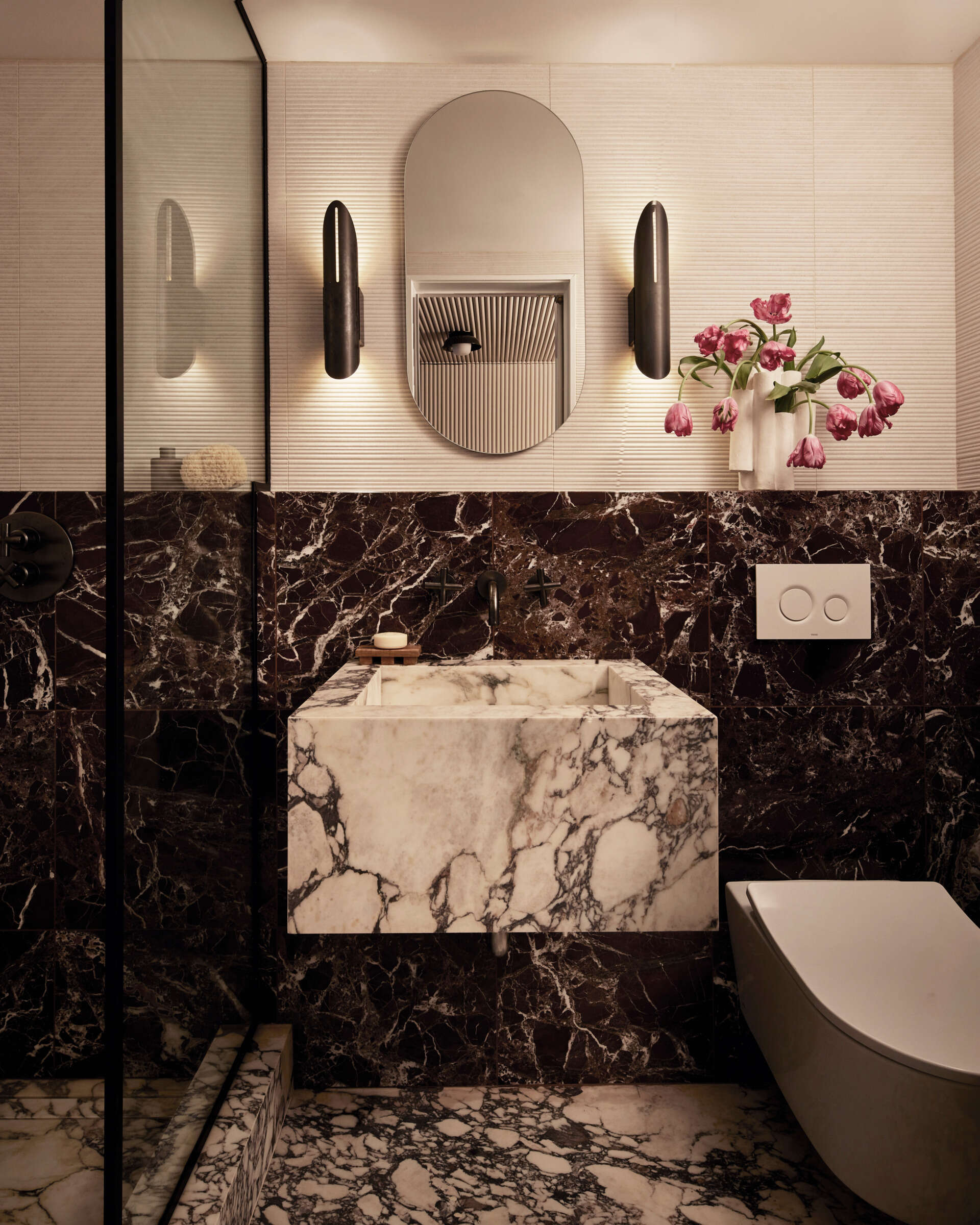 In this guest bath, espectaculo marble wraps both floor and walls, while rosa aurora stone tiles define the skylit tub and shower recess.