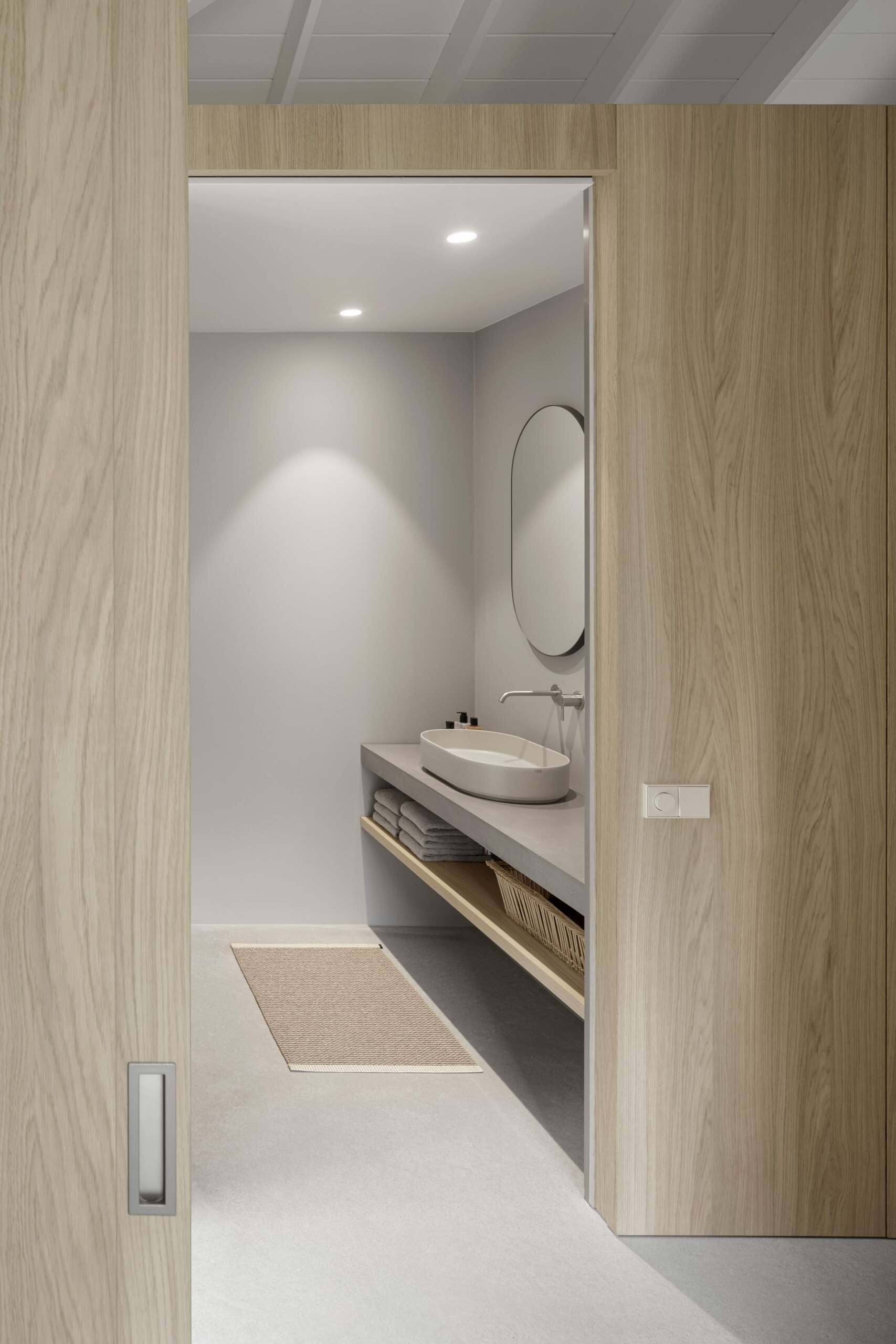 This bathroom continues the home’s theme of simplicity and refinement. Pale grey surfaces and clean lines offer comfort without excess. Thoughtful placement ensures easy access while preserving the private nature of this wing of the home.