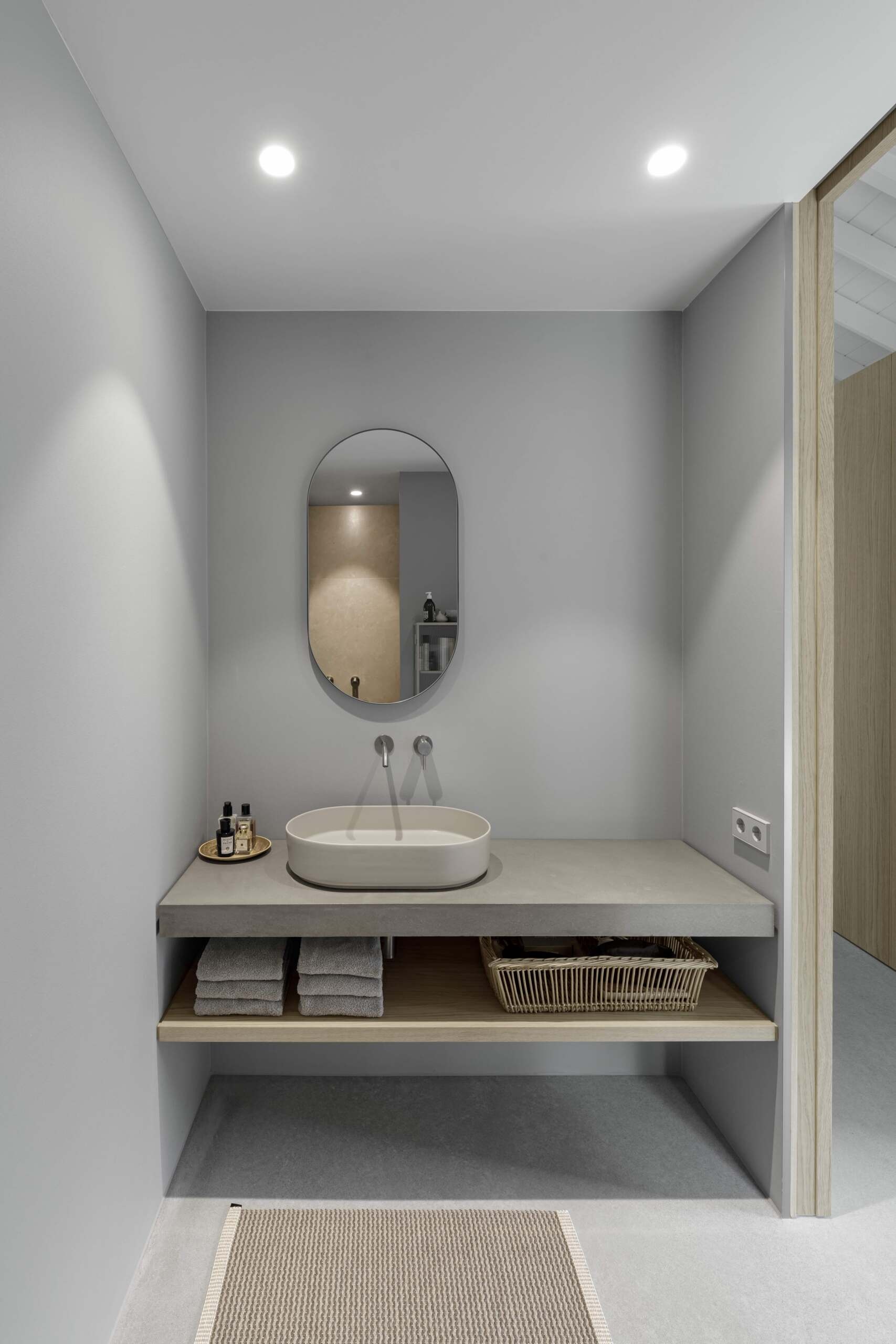 This bathroom continues the home’s theme of simplicity and refinement. Pale grey surfaces and clean lines offer comfort without excess. Thoughtful placement ensures easy access while preserving the private nature of this wing of the home.