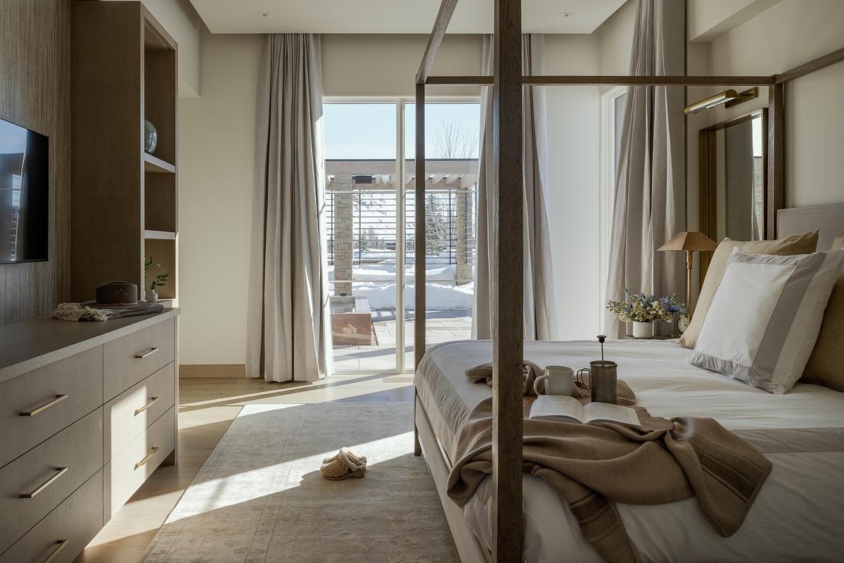 In this contemporary bedroom, large windows bring in soft natural light and frame views of the landscape, while layered textures create a serene atmosphere.