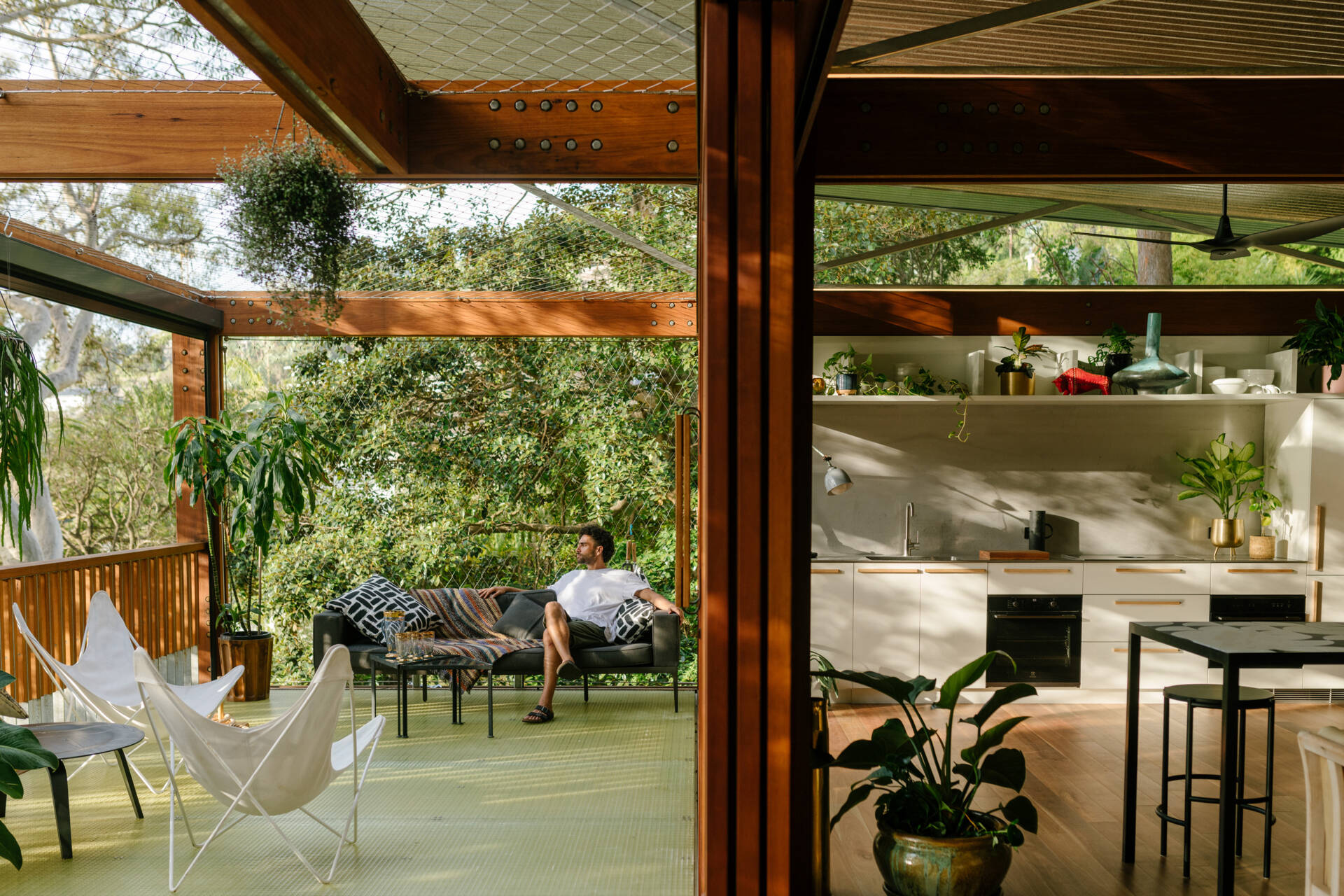 An extensive deck stretches around this home, creating multiple outdoor zones to sit, relax, or gather. Every corner of this house is a front-row seat to the treetops. Netted wire balustrades keep it light and open, while cushions and soft textures invite you to settle in.