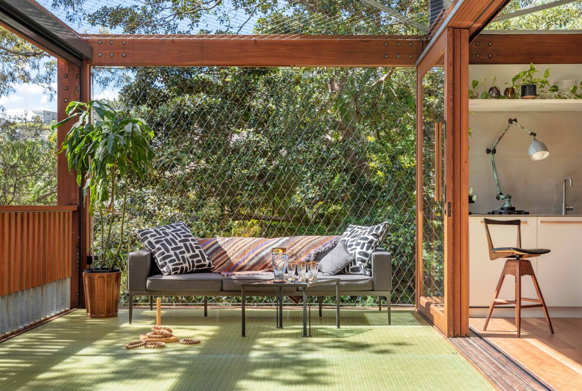 An extensive deck stretches around this home, creating multiple outdoor zones to sit, relax, or gather. Every corner of this house is a front-row seat to the treetops. Netted wire balustrades keep it light and open, while cushions and soft textures invite you to settle in.