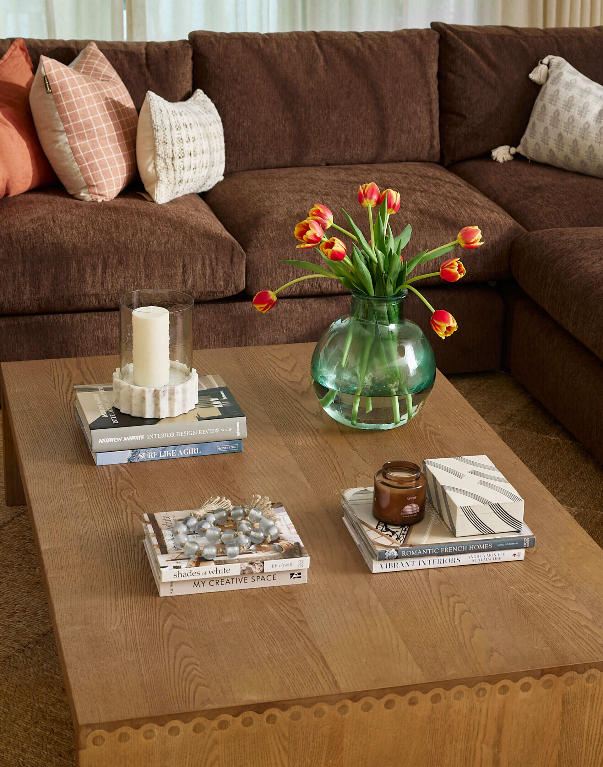 Earthy tones and soft textures define this serene living room. A deep brown sectional, wood coffee table, blush accents, and a neutral rug creates a cozy, light-filled space perfect for everyday comfort.