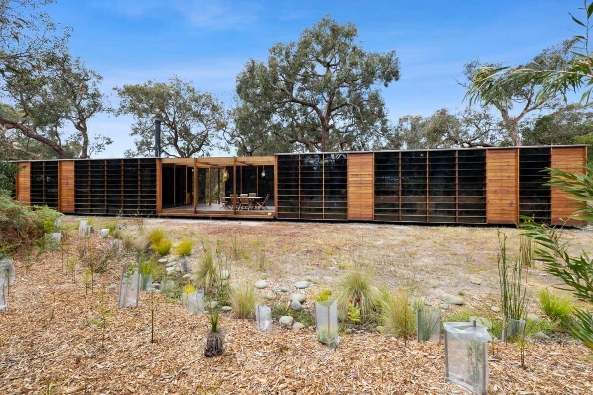A recycled timber home and studio built with passive solar principles and reclaimed materials. It features two pavilions, full-height glazing, and a bluestone terrace set beneath native trees.