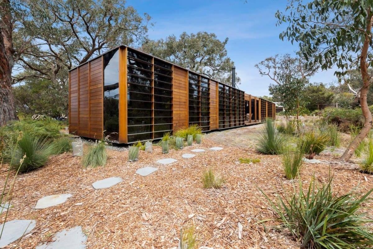A recycled timber home and studio built with passive solar principles and reclaimed materials. It features two pavilions, full-height glazing, and a bluestone terrace set beneath native trees.