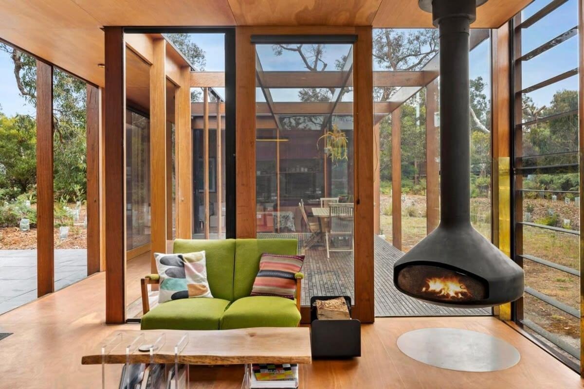 A modern rural home with wood framing and a hanging fireplace.