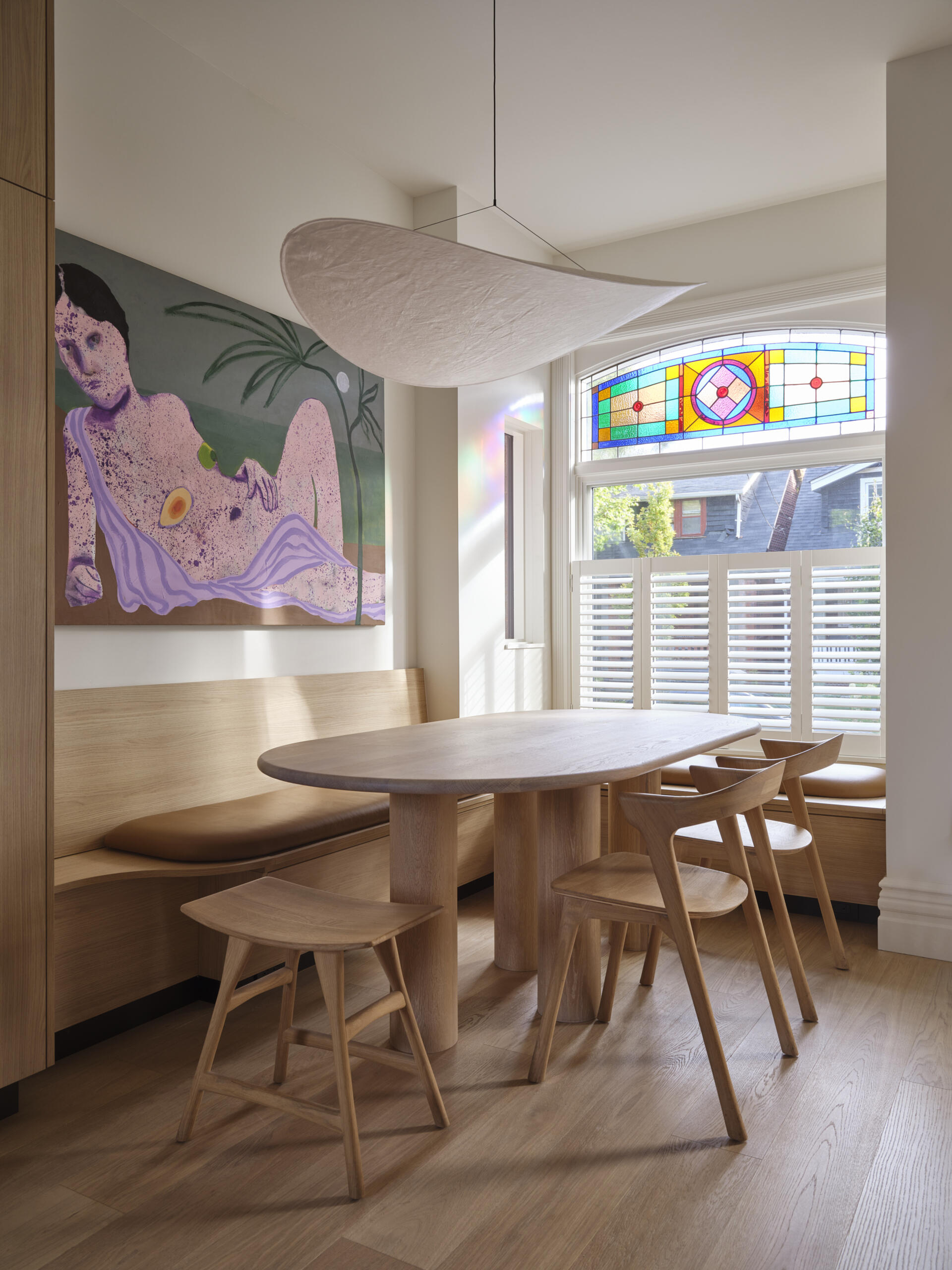 This curved dining banquette fits perfectly within a bay window, offering a cozy spot for everyday meals in a renovated Victorian home.