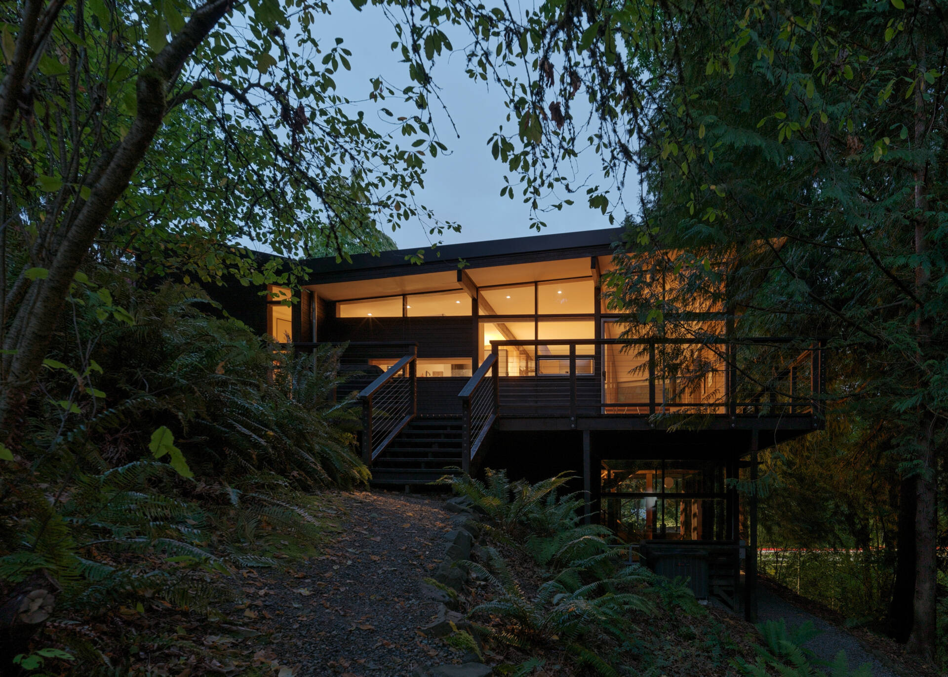 Tucked beside a creek in the Seattle woods, this Mid-Century Modern home feels like a private treehouse. The forest path to the front door sets the tone for a peaceful, nature-connected retreat.