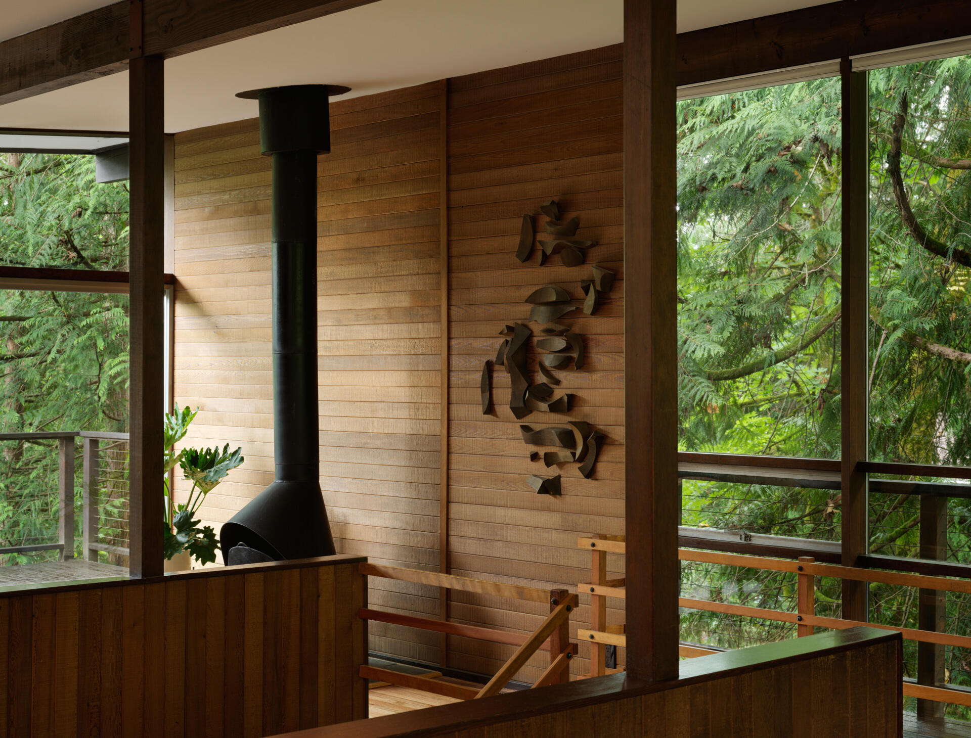 This Mid-Century Modern living room blends art and architecture with floor-to-ceiling windows, a striking steel fireplace, and original works by Alden Mason. Nature and design meet in a space full of light and intention.