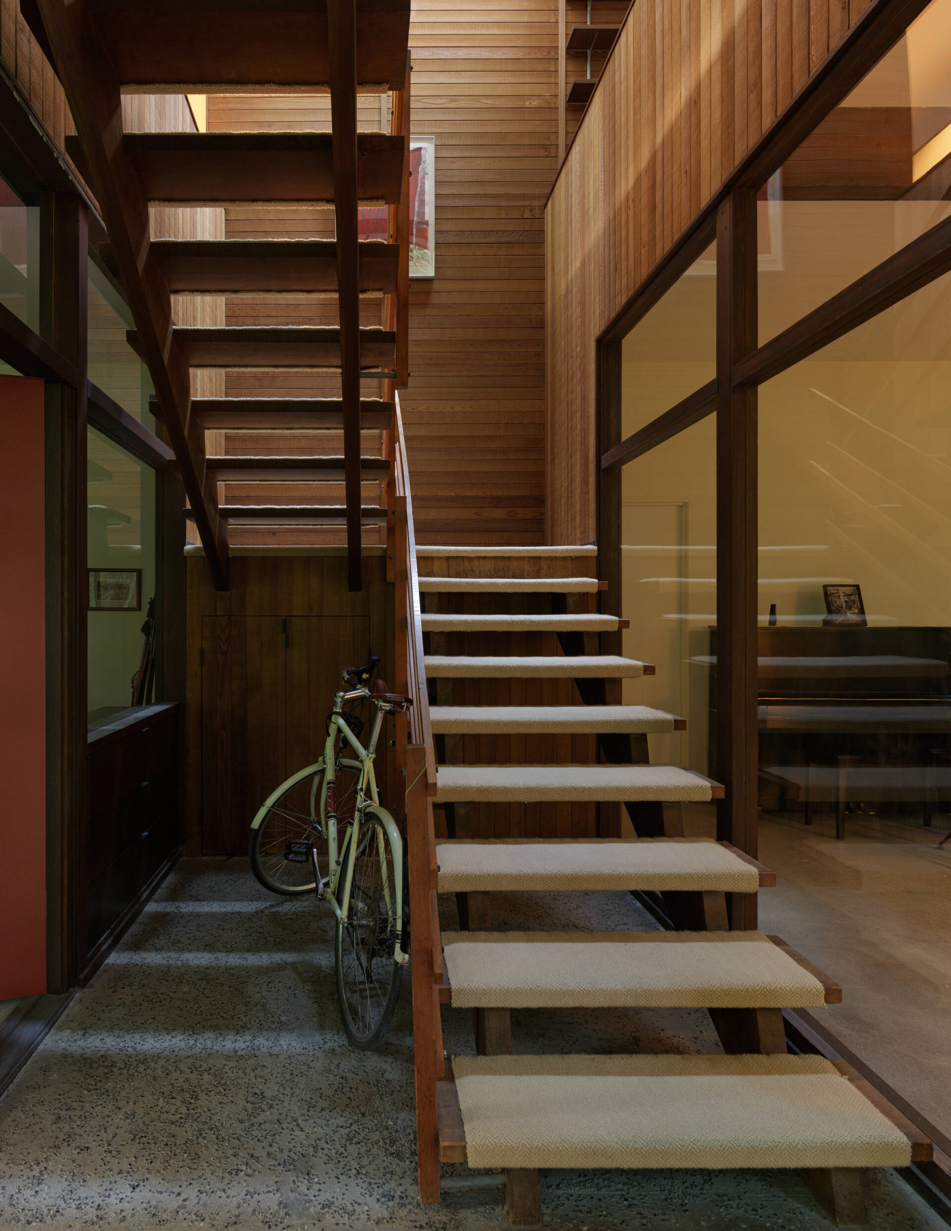 Once a studio for Alden Mason, this creative corner of the Mid-Century Modern home now serves as a music room. Nearby, the open-tread stairs rise through sunlight beneath a bold Rauschenberg print.