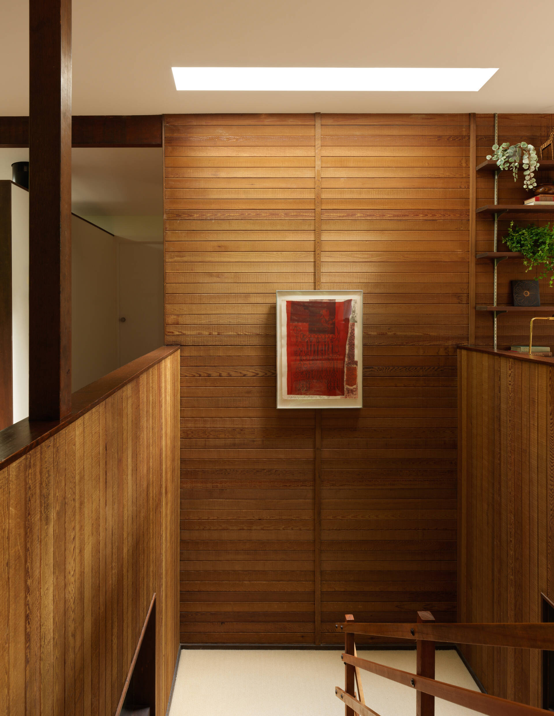 Once a studio for Alden Mason, this creative corner of the Mid-Century Modern home now serves as a music room. Nearby, the open-tread stairs rise through sunlight beneath a bold Rauschenberg print.