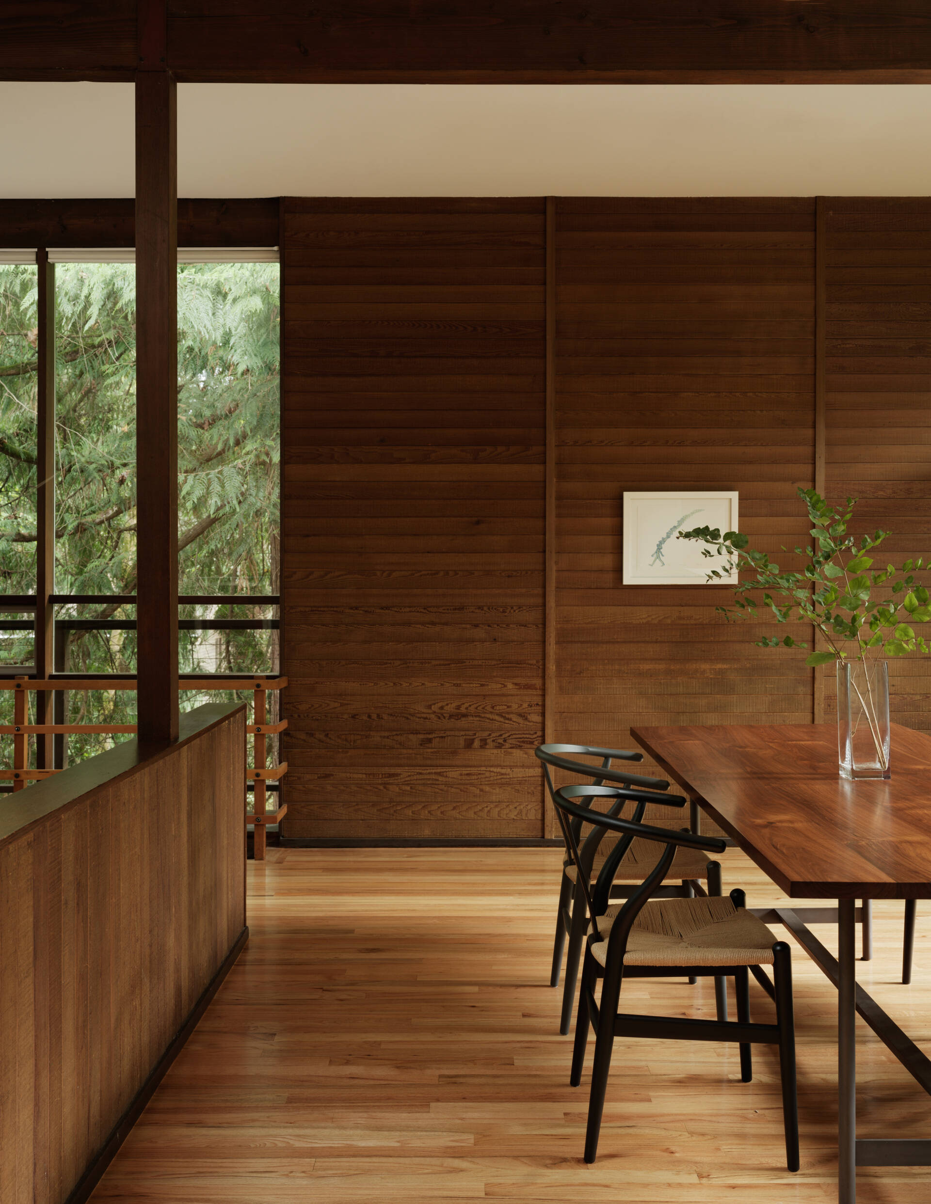 A curated Mid-Century Modern dining room featuring art by Do Ho Suh, a handcrafted Chadhaus table, and panoramic woodland views. It’s calm, warm, and built for connection.