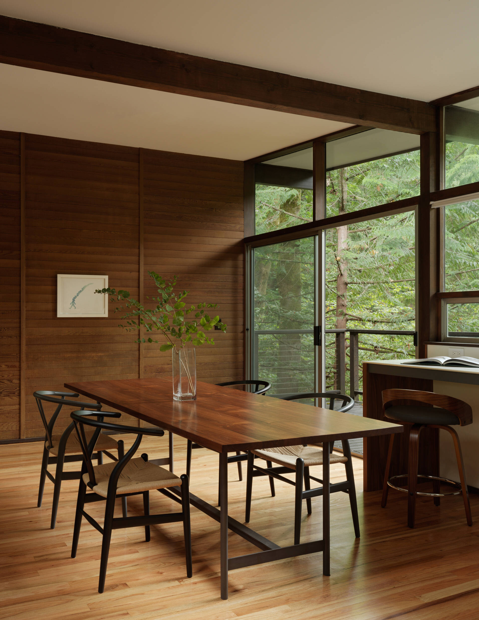 A curated Mid-Century Modern dining room featuring art by Do Ho Suh, a handcrafted Chadhaus table, and panoramic woodland views. It’s calm, warm, and built for connection.