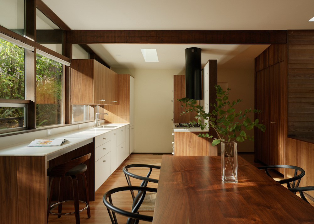 This Mid-Century Modern inspired kitchen pairs white laminate with walnut cabinetry and introduces a new skylight for natural brightness. Clean lines and timeless materials elevate the design.