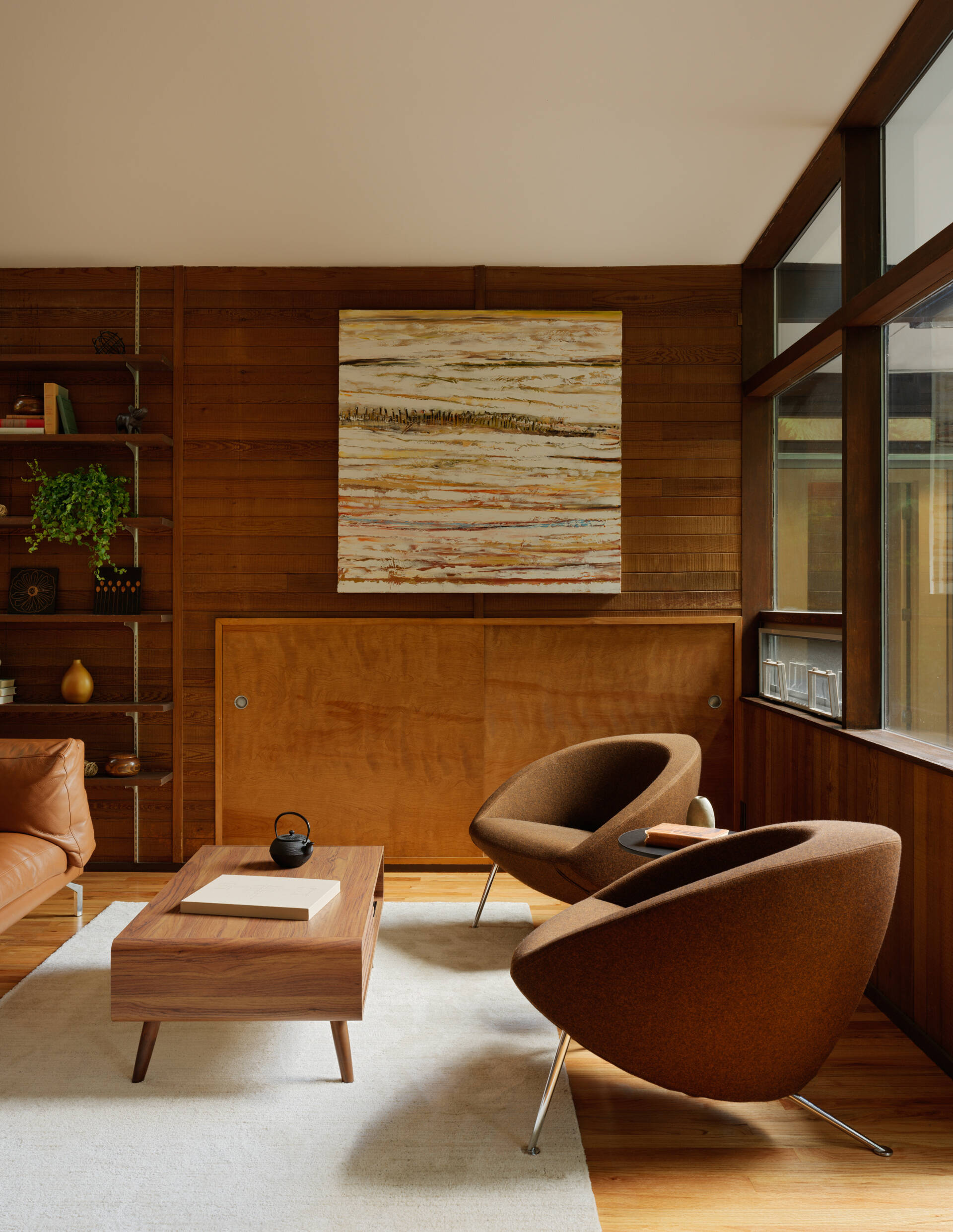  This Mid-Century Modern living room blends art and architecture with floor-to-ceiling windows, and a striking steel fireplace. Nature and design meet in a space full of light and intention.