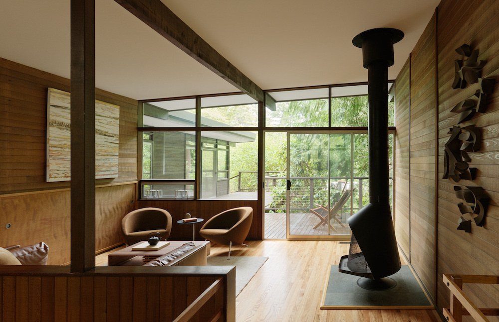  This Mid-Century Modern living room blends art and architecture with floor-to-ceiling windows, a striking steel fireplace, and original works by Alden Mason. Nature and design meet in a space full of light and intention.