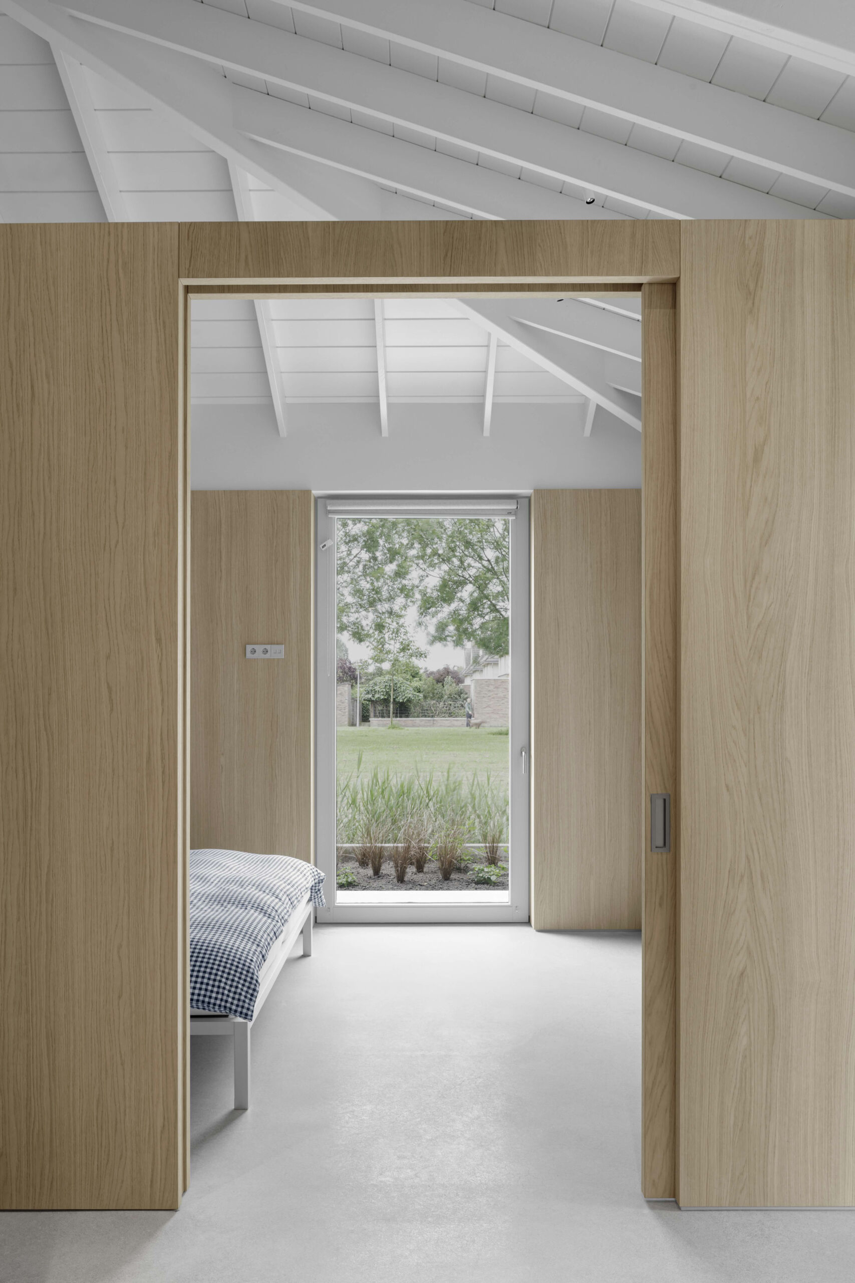 This bedroom, located on the north side, is quiet and calm. Light oak walls and expansive windows create a restorative atmosphere. Privacy is assured, yet the bedroom still benefits from garden views and the overall openness of the floor plan.