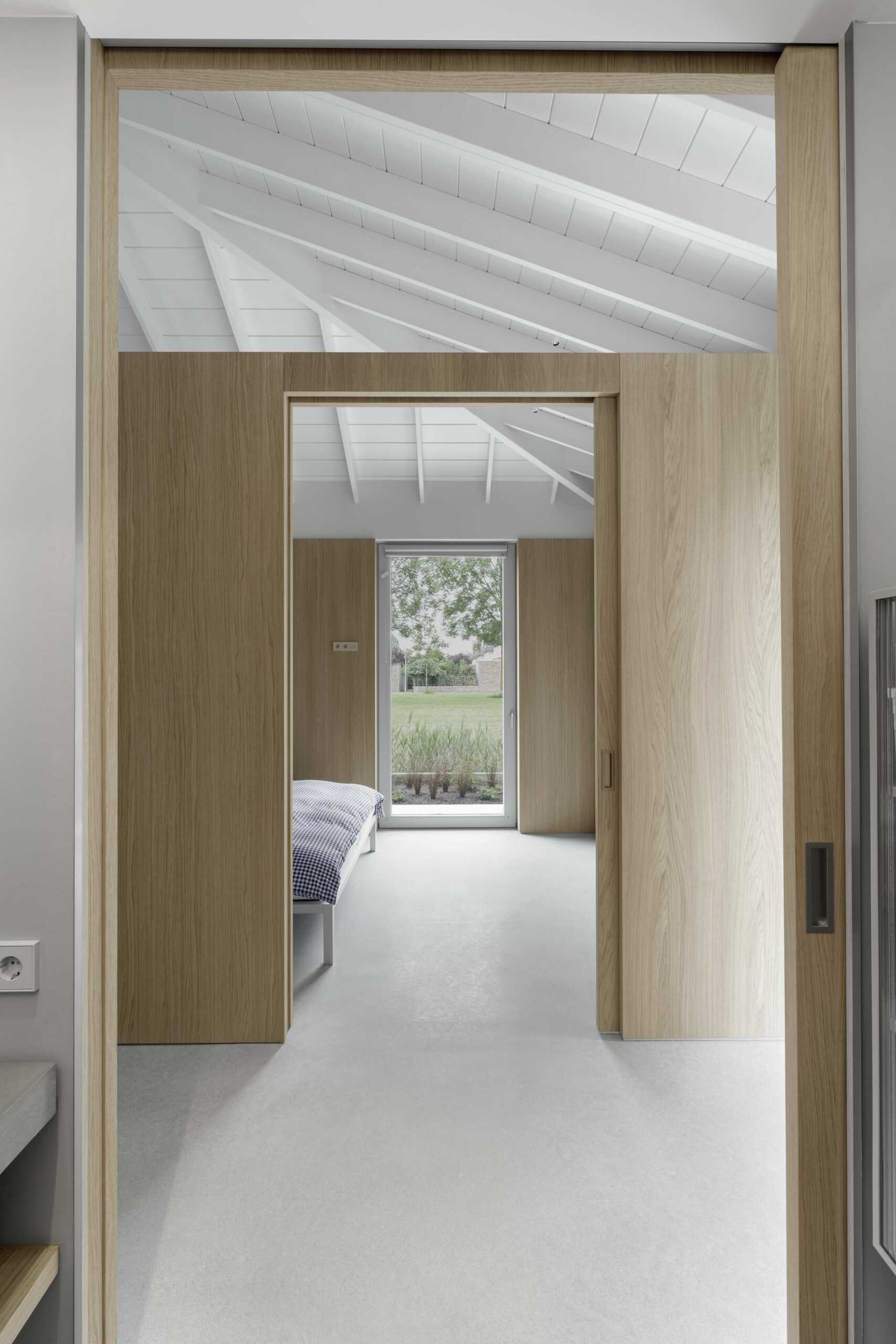 This bedroom, located on the north side, is quiet and calm. Light oak walls and expansive windows create a restorative atmosphere. Privacy is assured, yet the bedroom still benefits from garden views and the overall openness of the floor plan.