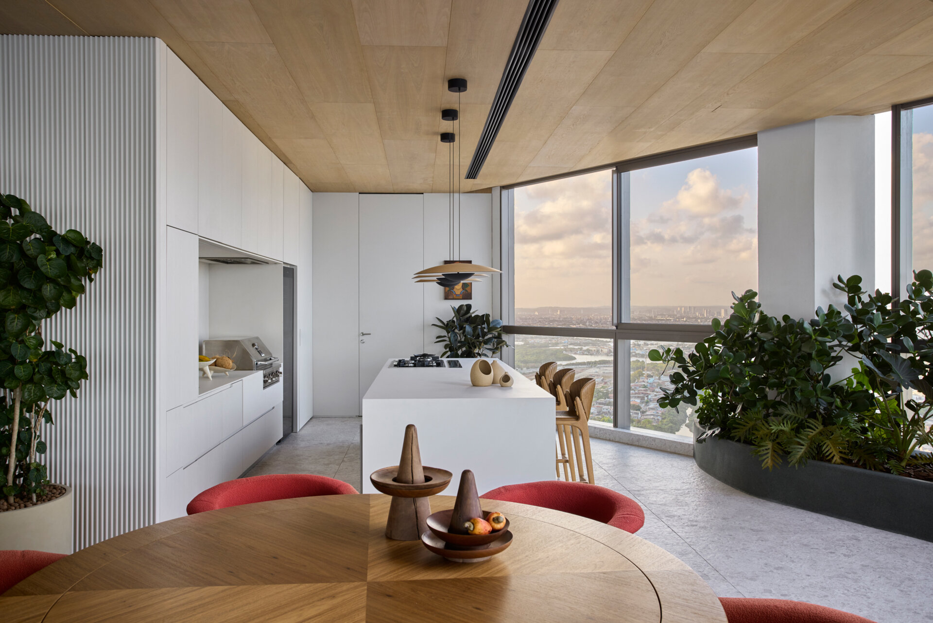 The kitchen and barbecue area share the upper floor with the main social spaces. The kitchen features a countertop clad natural stone, while the blue cabinetry echoes the tones of the sea. Materials and layout of the barbecue area emphasize openness and continuity, with finishes chosen to unify the communal areas.