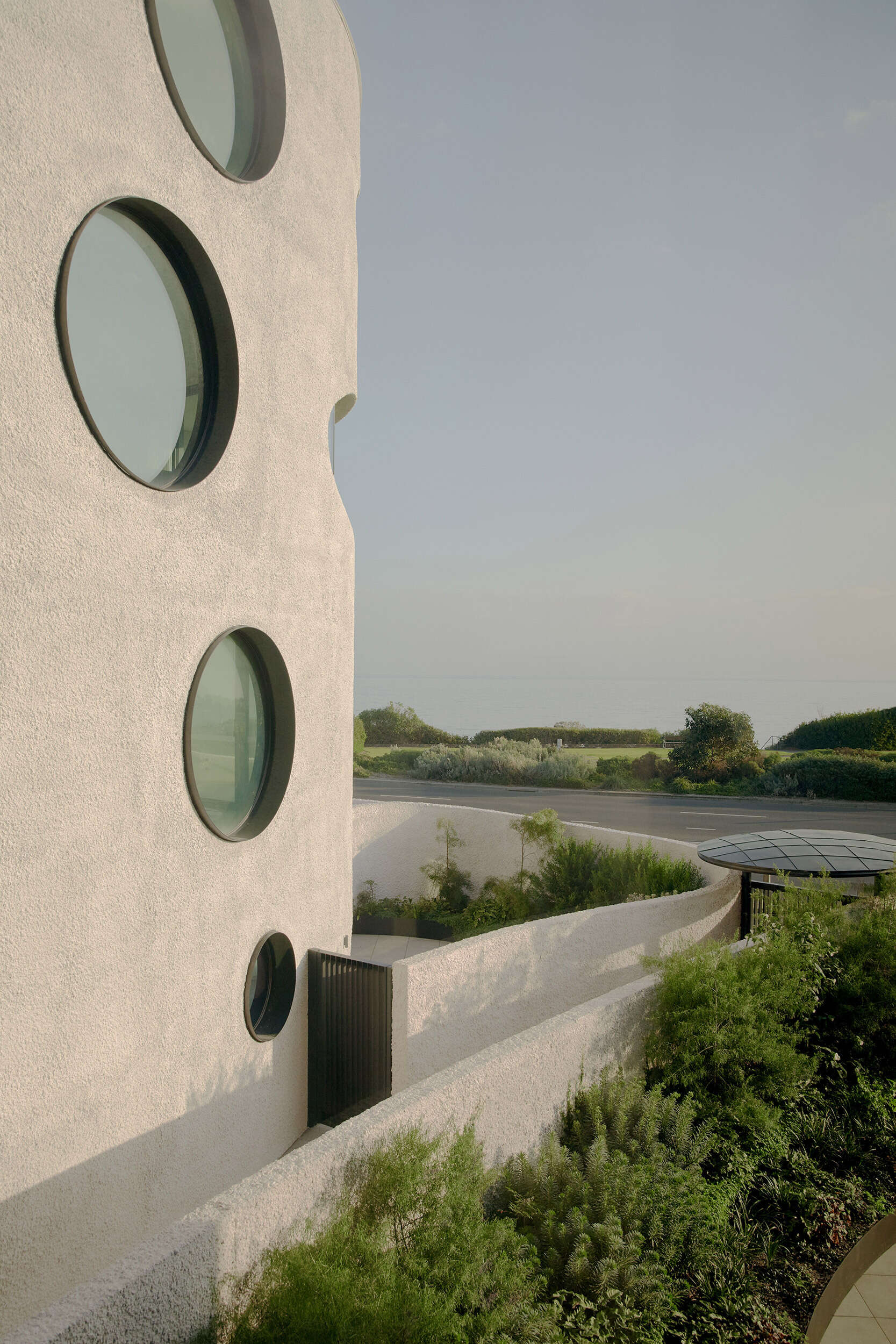 A lush native garden runs through the site, creating a green spine that links all four pavilions, softens the architecture, and connects residents to the coastal setting.