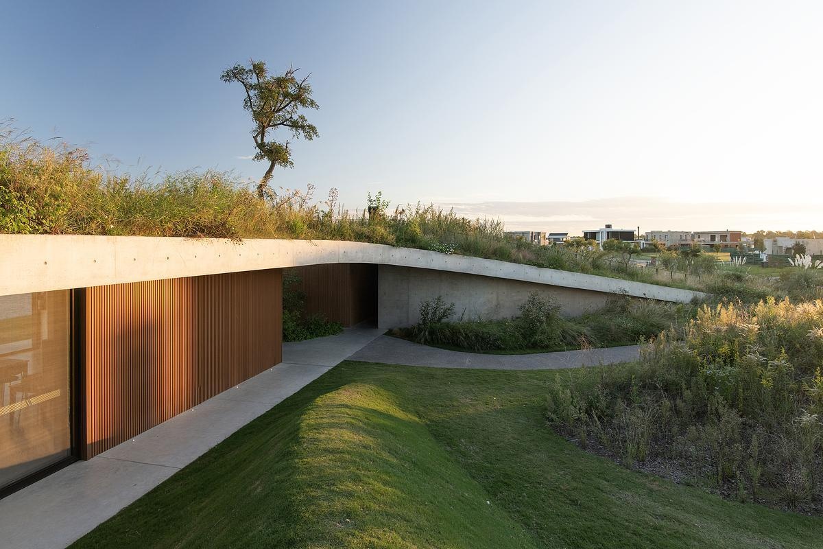 This concrete shell of this modern club house does double duty: it acts as both the building’s structure and surface, minimizing visual clutter and material use. The result is a continuous architectural form that feels quiet yet confident, merging seamlessly with its environment while inviting people to explore, gather, and linger.